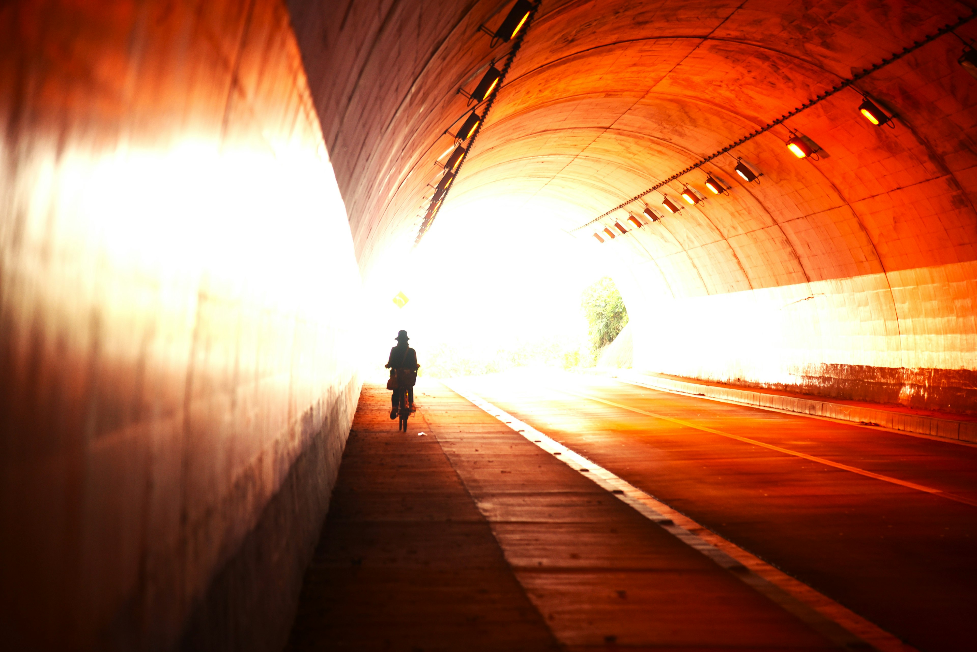 A silhouette of a person walking towards a bright exit in a tunnel