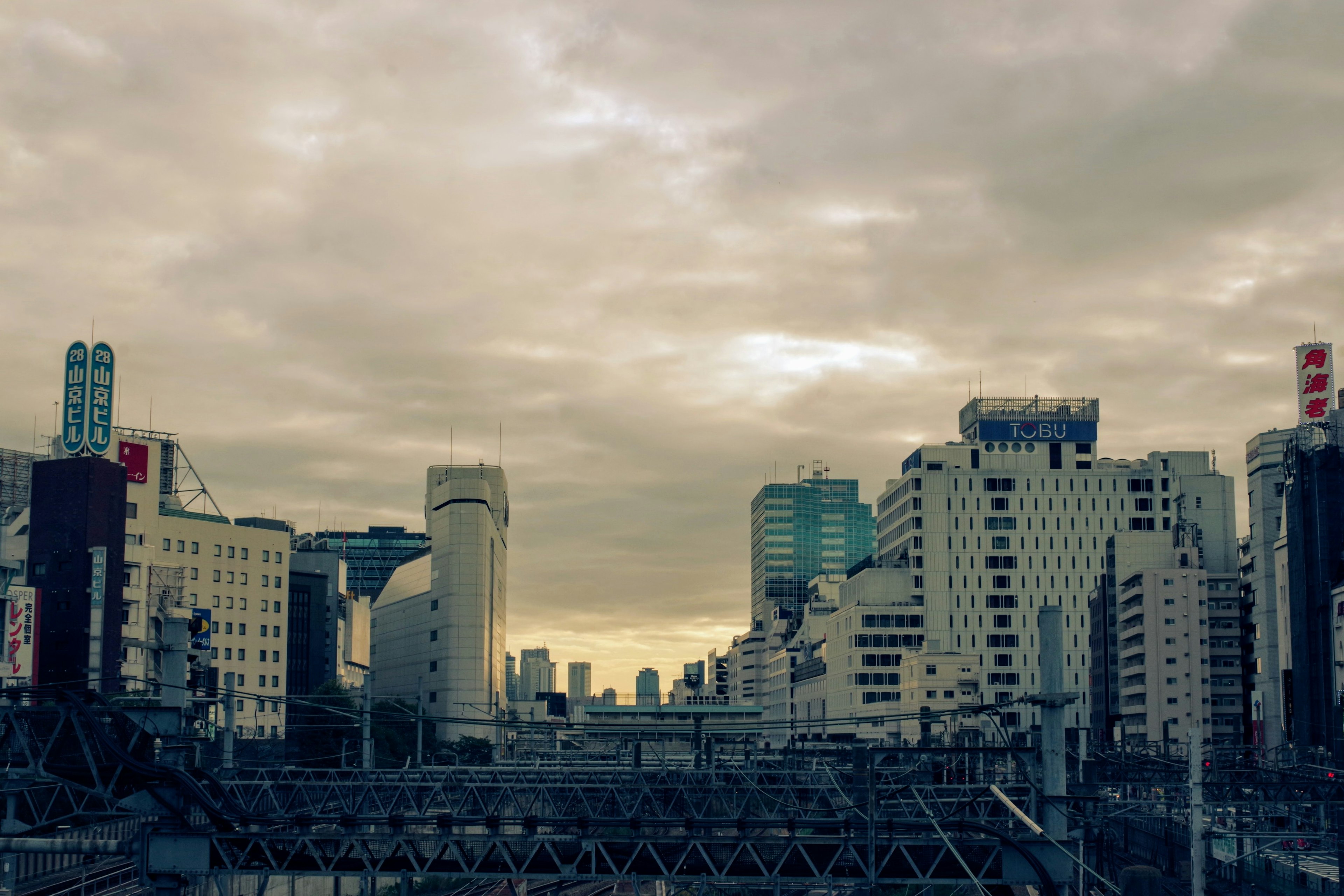 City skyline with high-rise buildings and railway under a cloudy sky