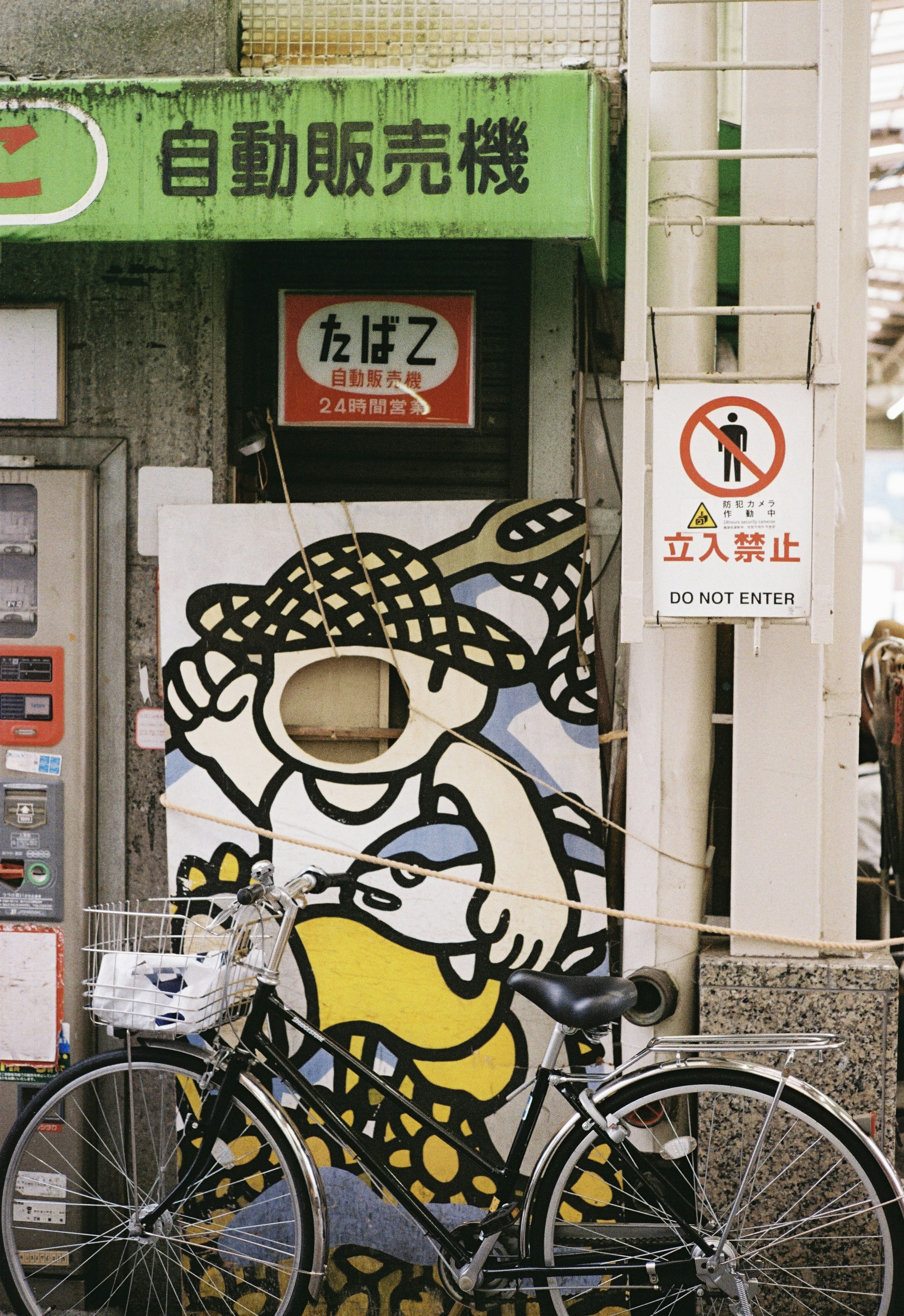 A vending machine with a character illustration and a bicycle in front