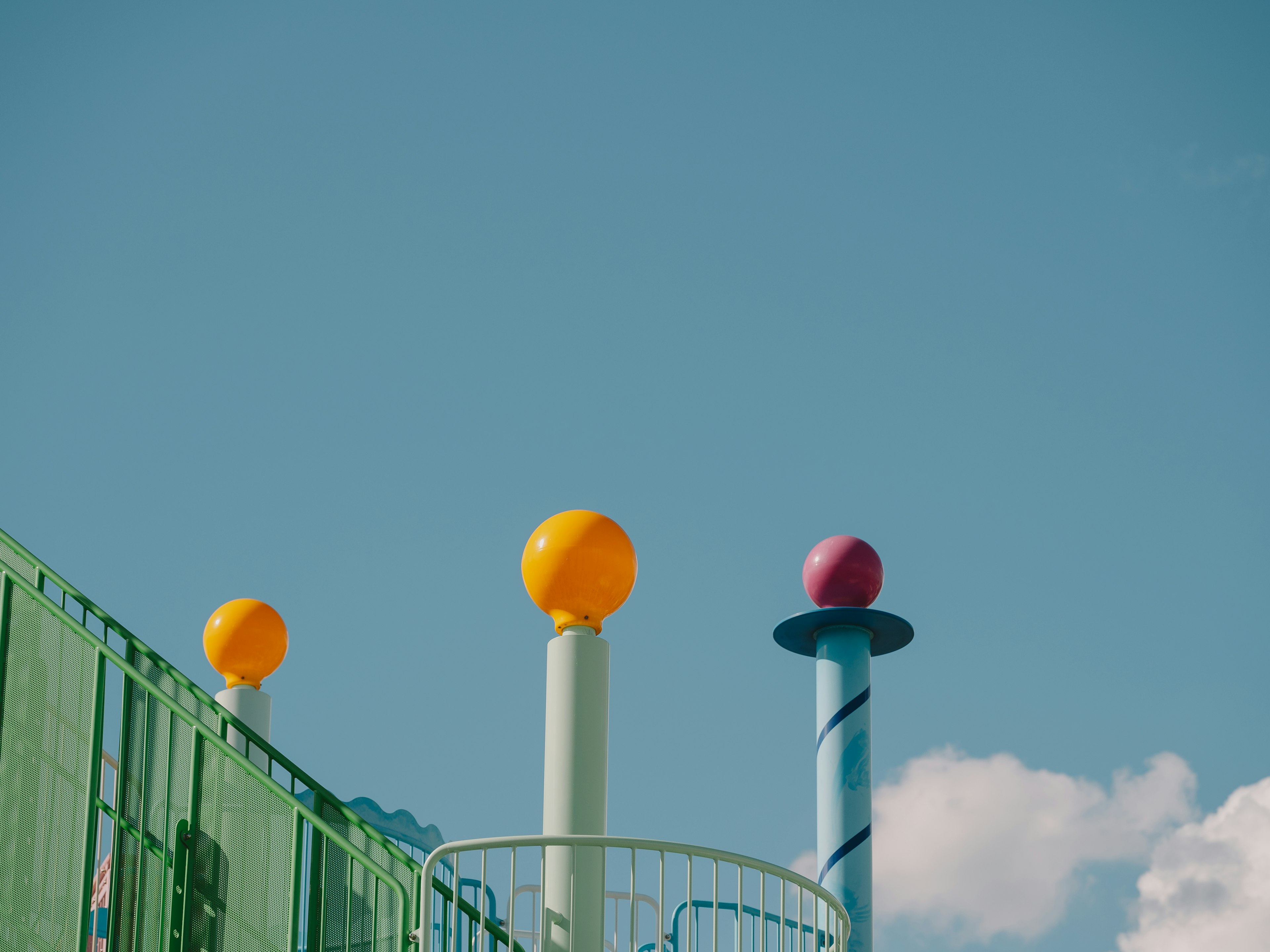 Bunte Spielplatzpfosten mit Kugeln vor blauem Himmel