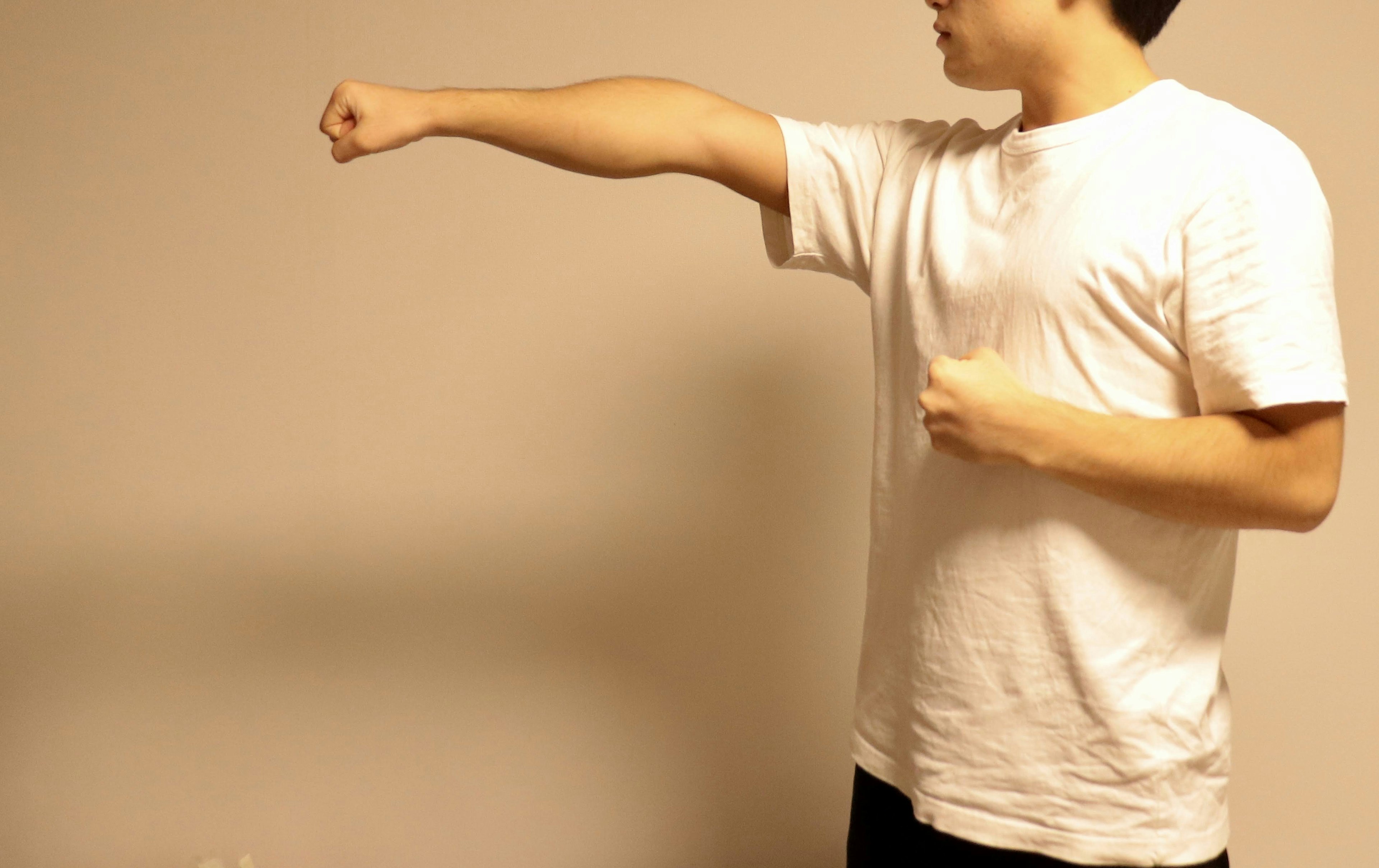 A man in a white t-shirt extending his arm with a clenched fist