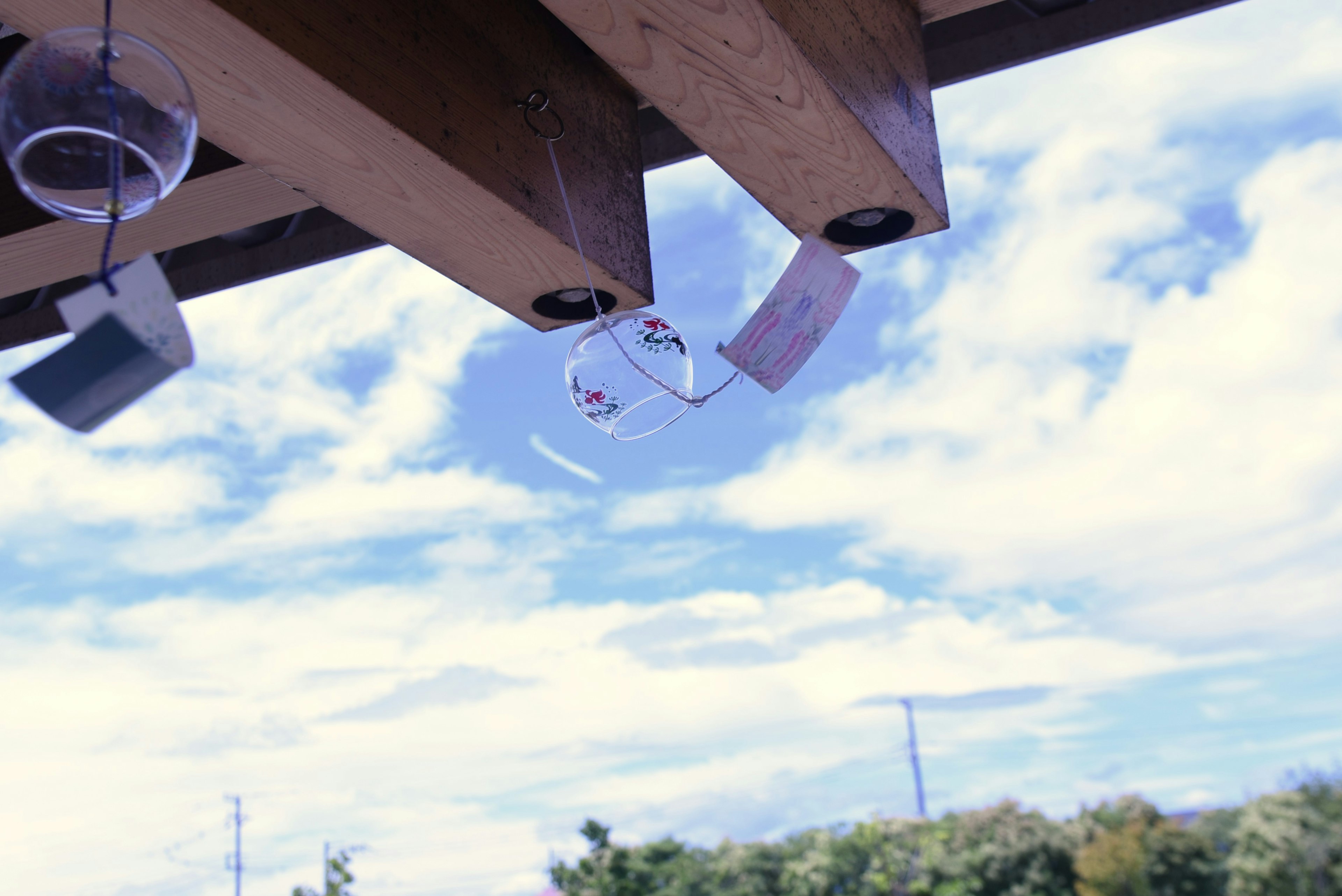 Cups hanging from wooden beams under a blue sky