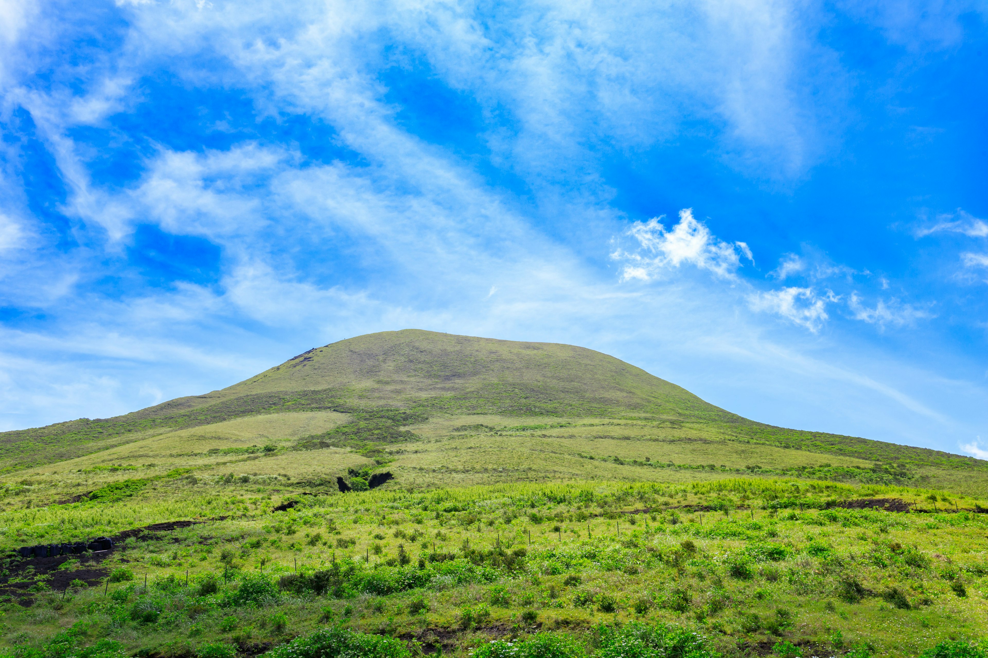 Un paisaje montañoso sereno rodeado de hierba verde y un cielo azul