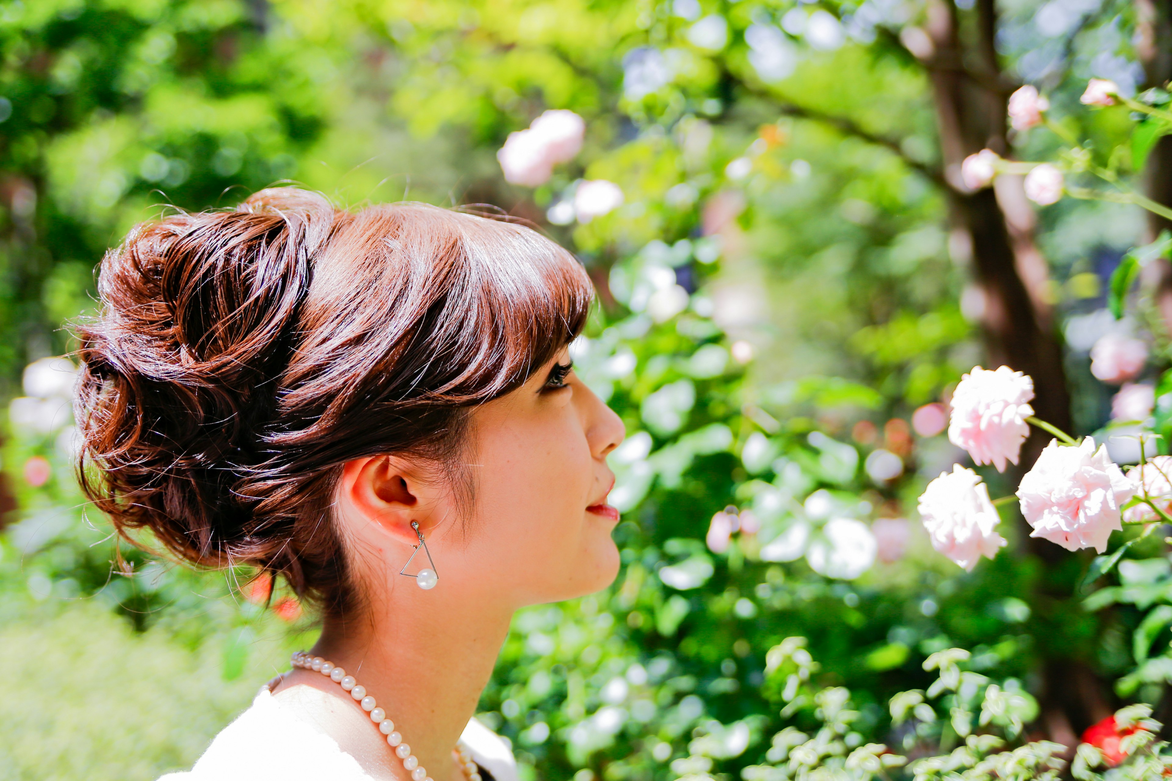 Una hermosa mujer mirando rosas en un entorno verde