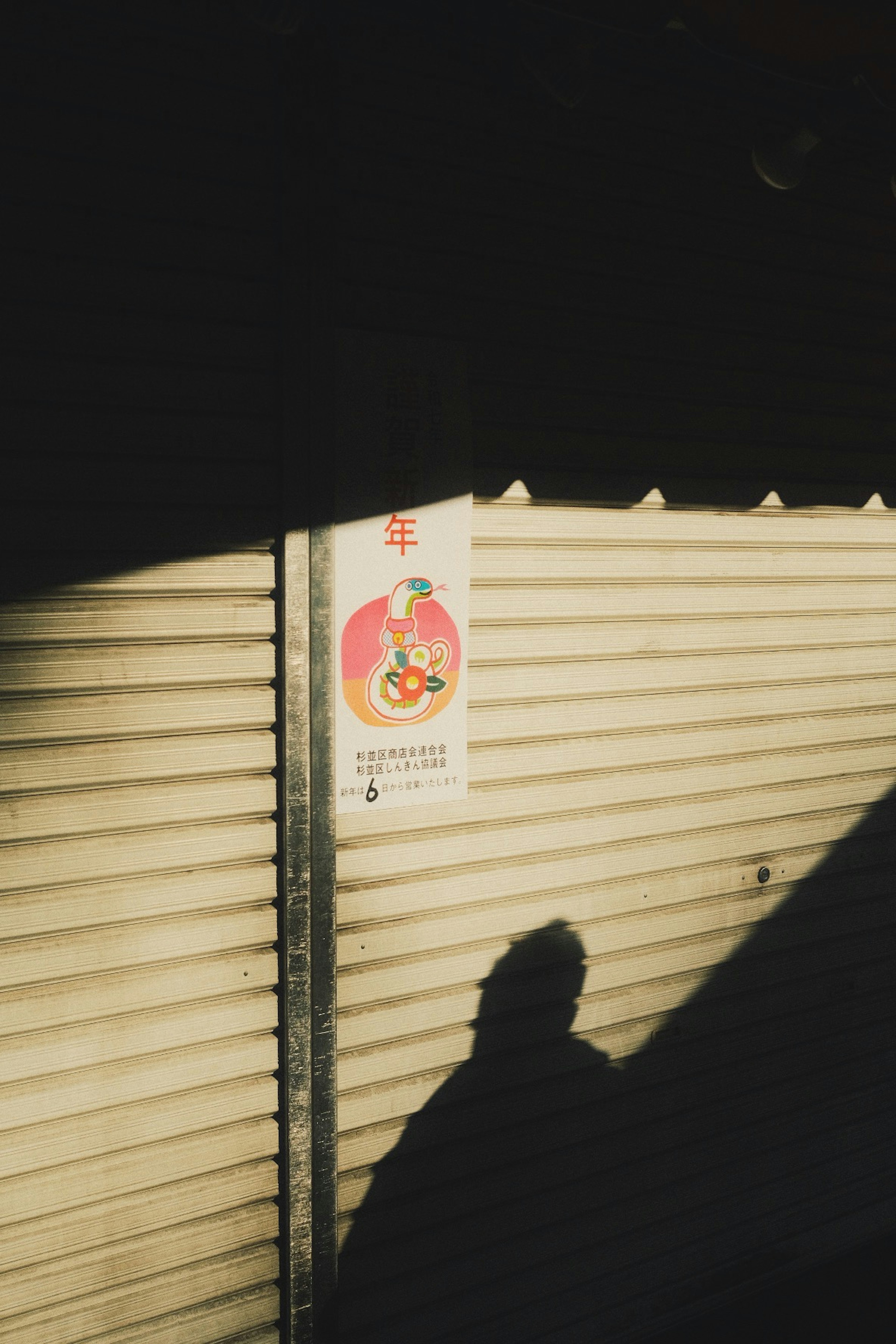 A wall with a shadow and a colorful poster