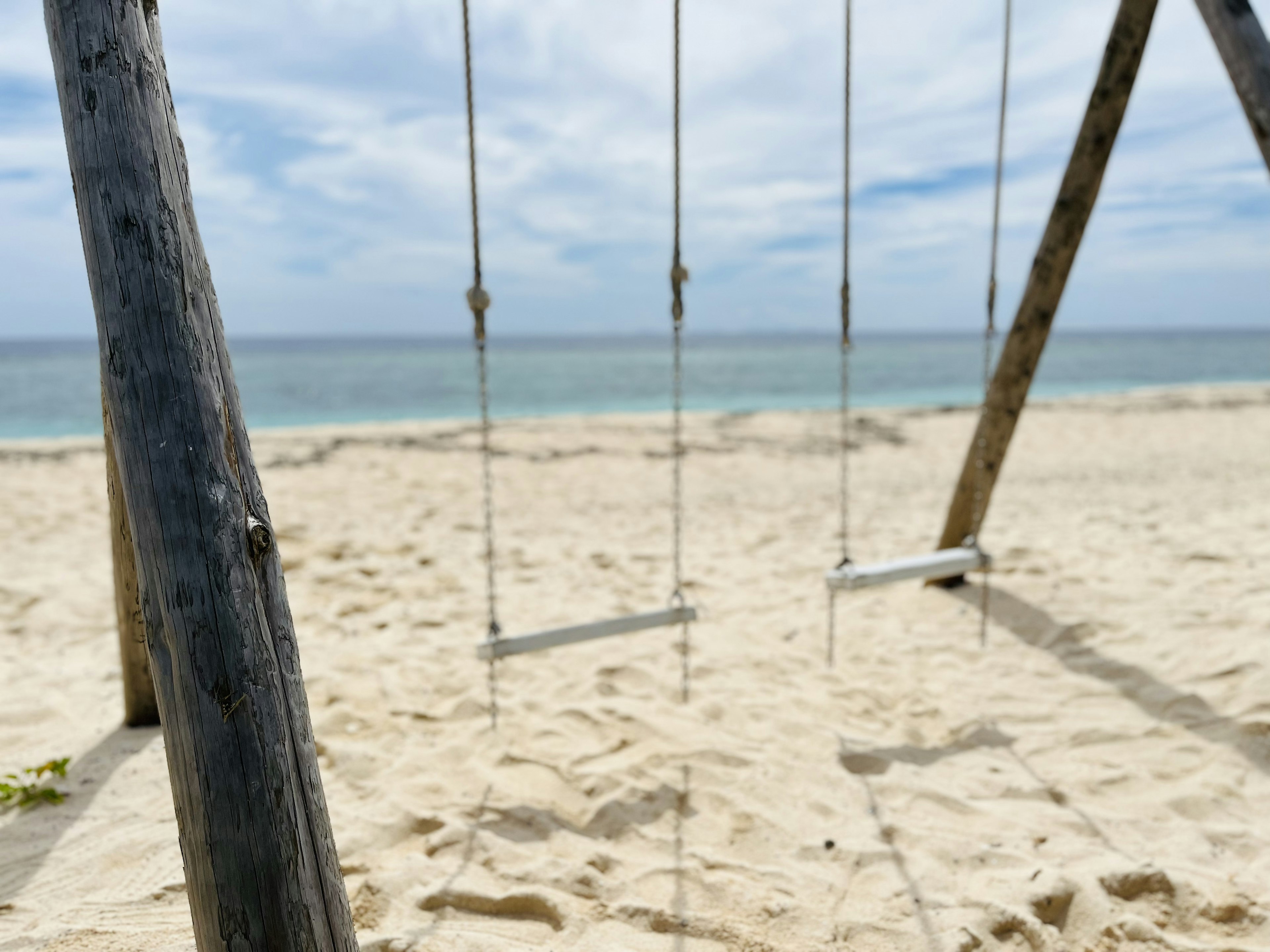 Swing set on a sandy beach with ocean view