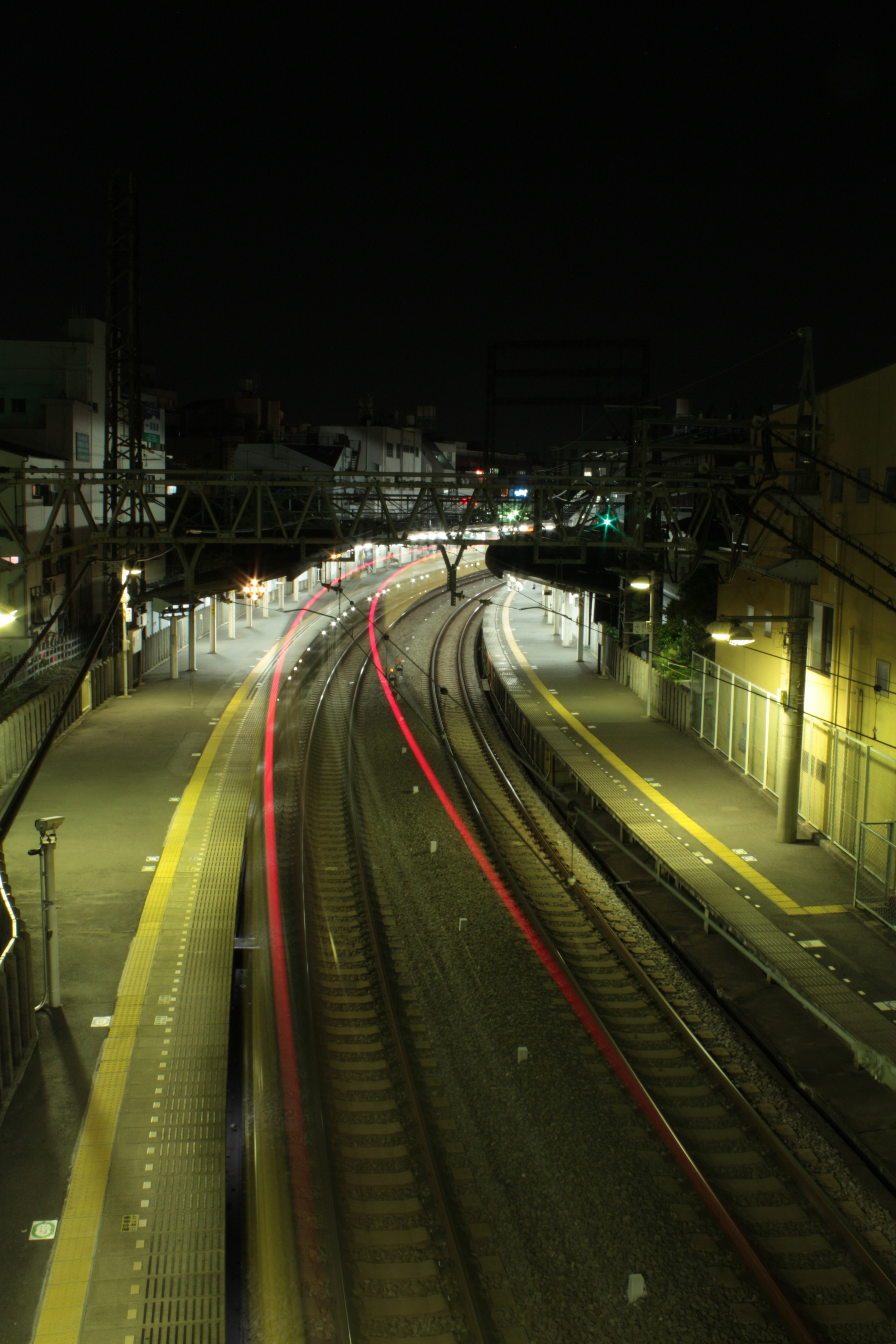 Stazione ferroviaria notturna con tracce di luce e binari curvi