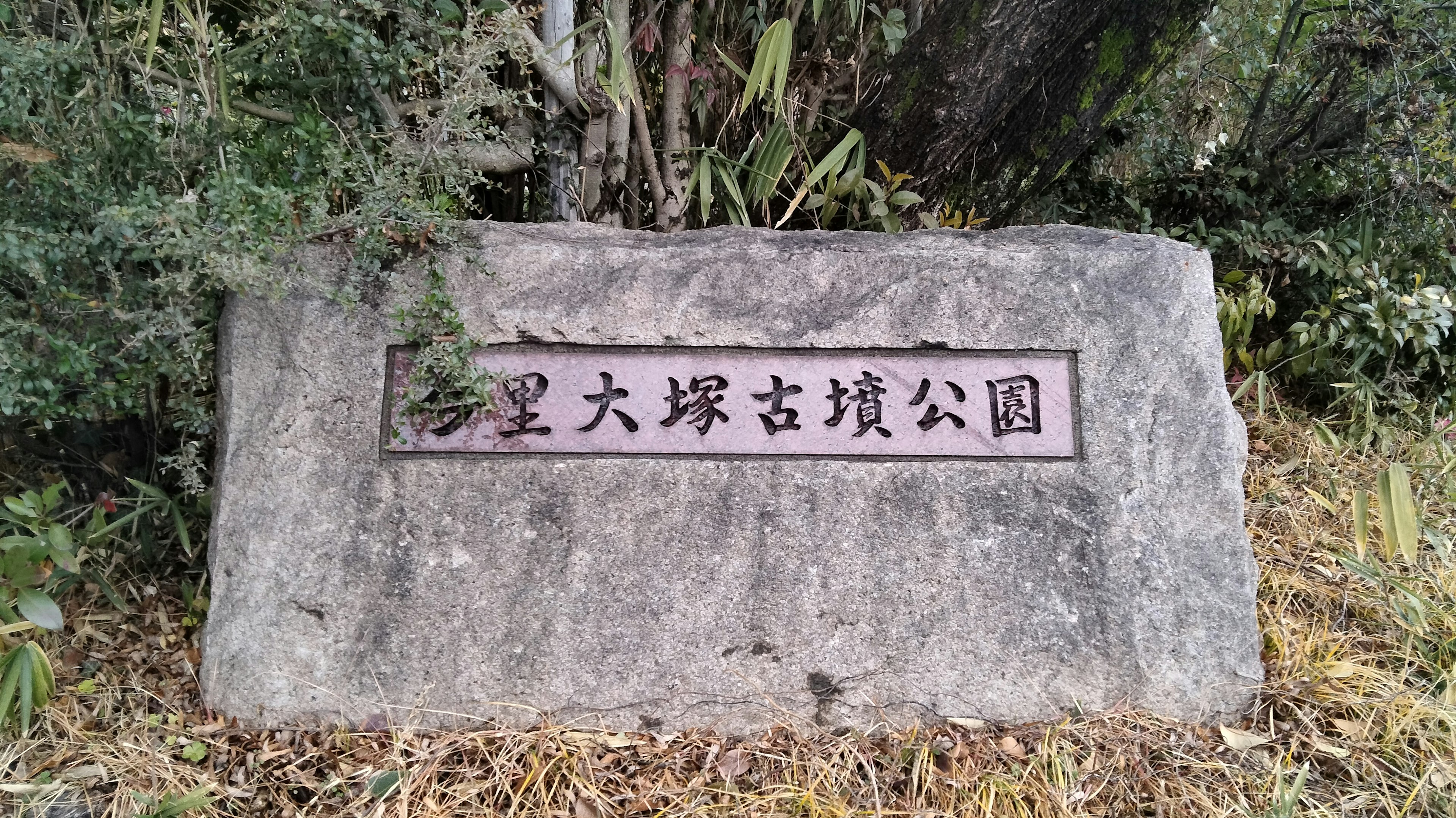 Monumento de piedra que muestra el nombre de un parque rodeado de naturaleza