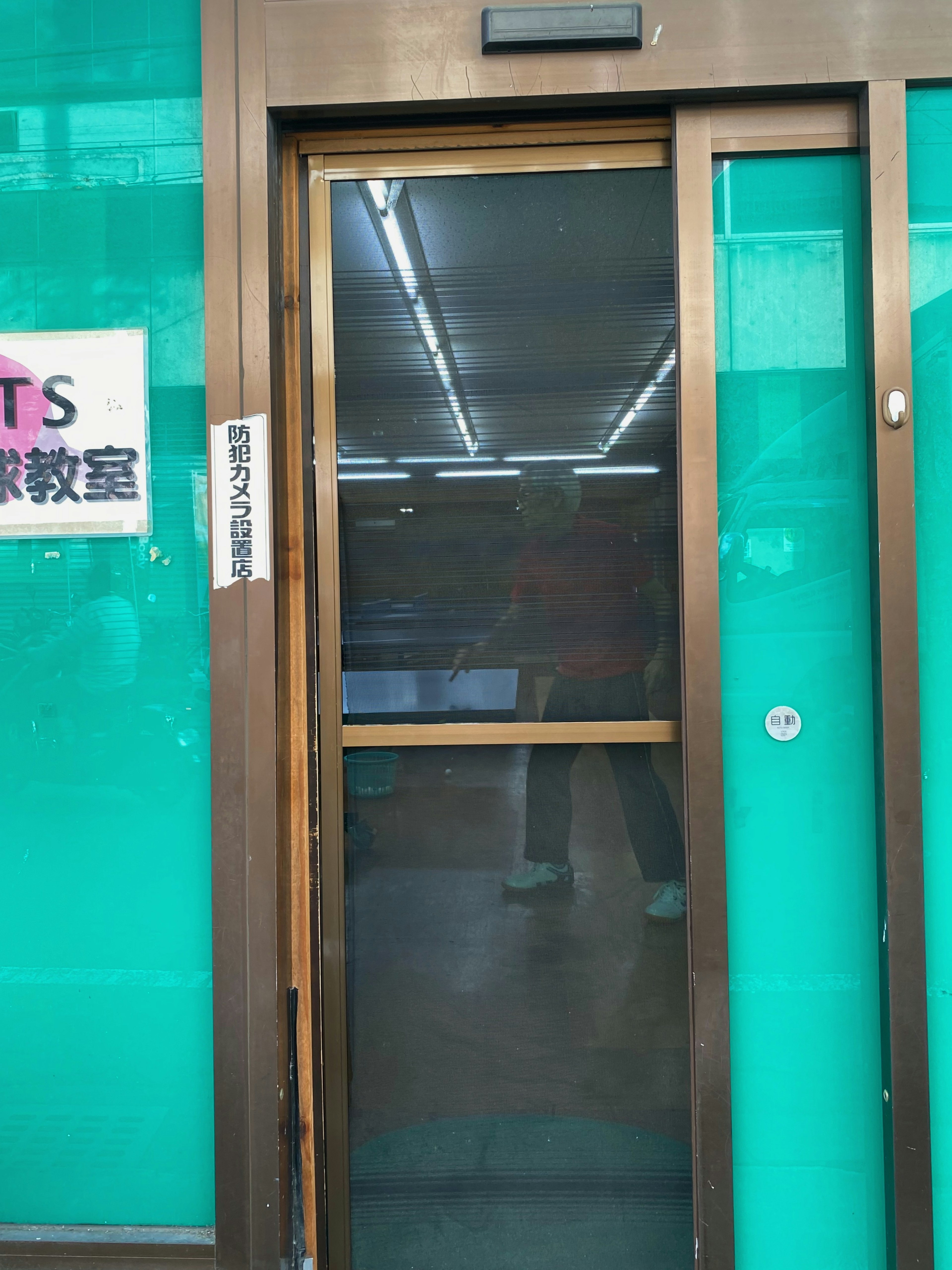 Automatic door surrounded by green glass with visible interior lighting