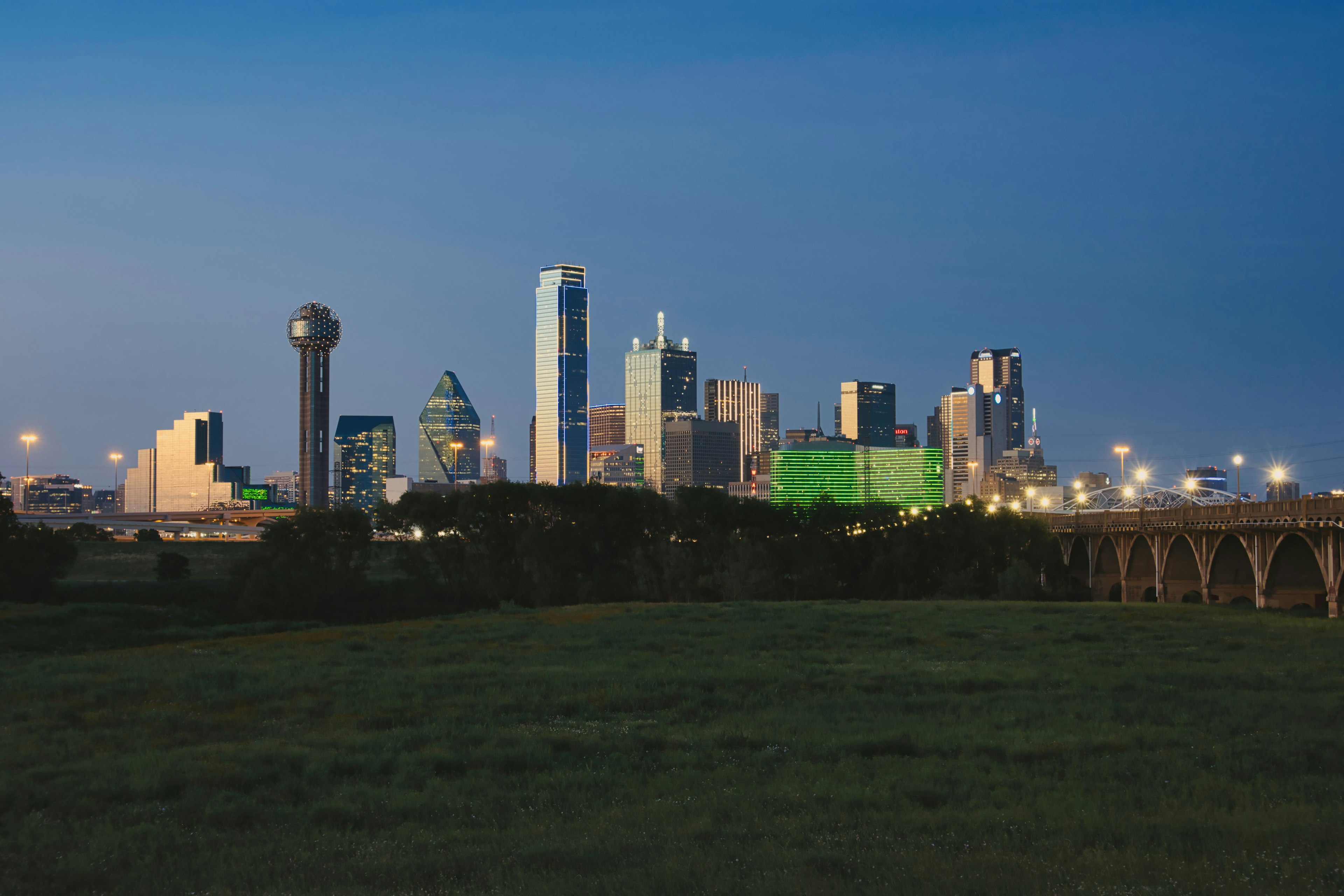 Horizonte de Dallas al anochecer, siluetas de rascacielos, cielo azul, edificio verde