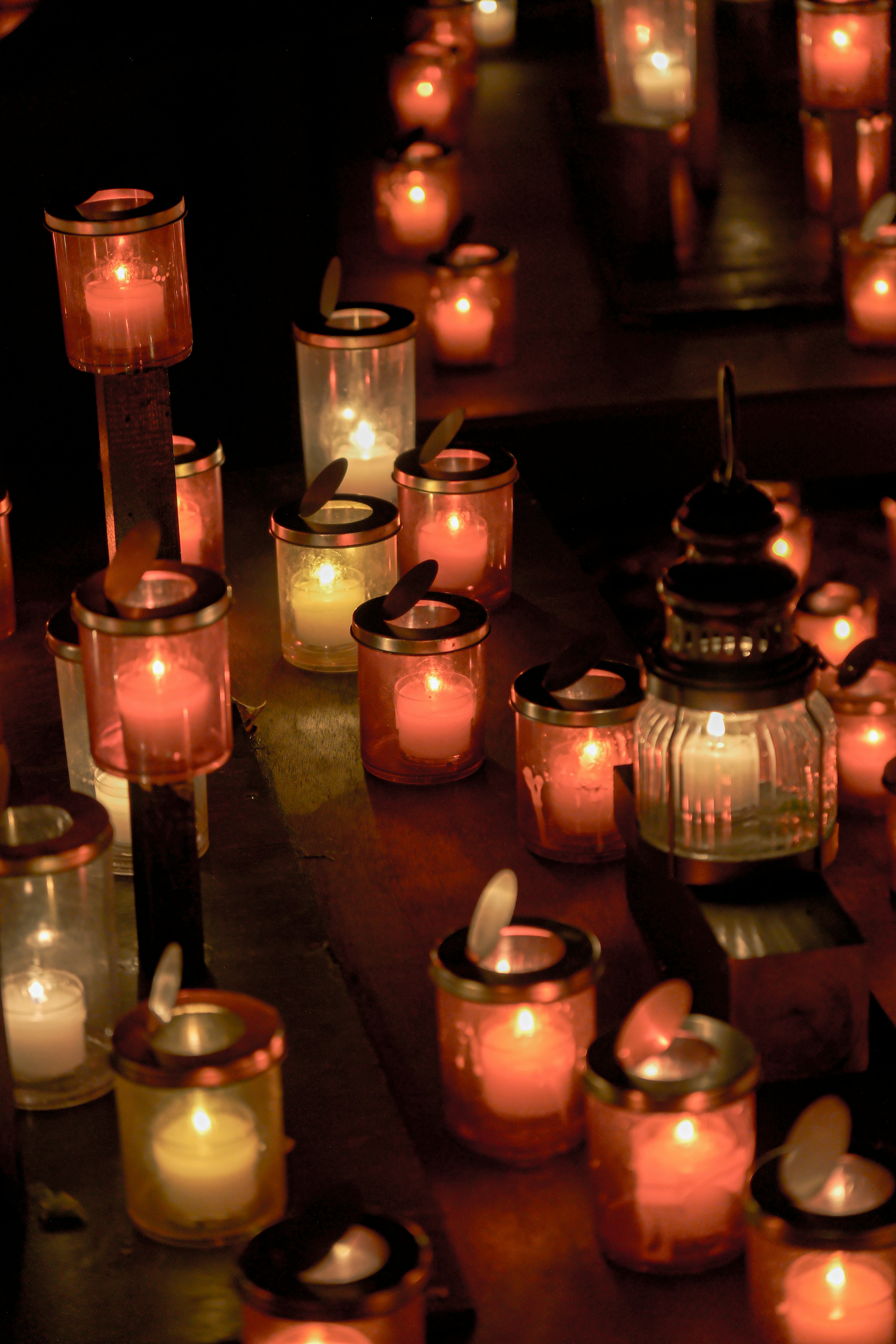 Una colección de velas y faroles brillando en varios colores por la noche