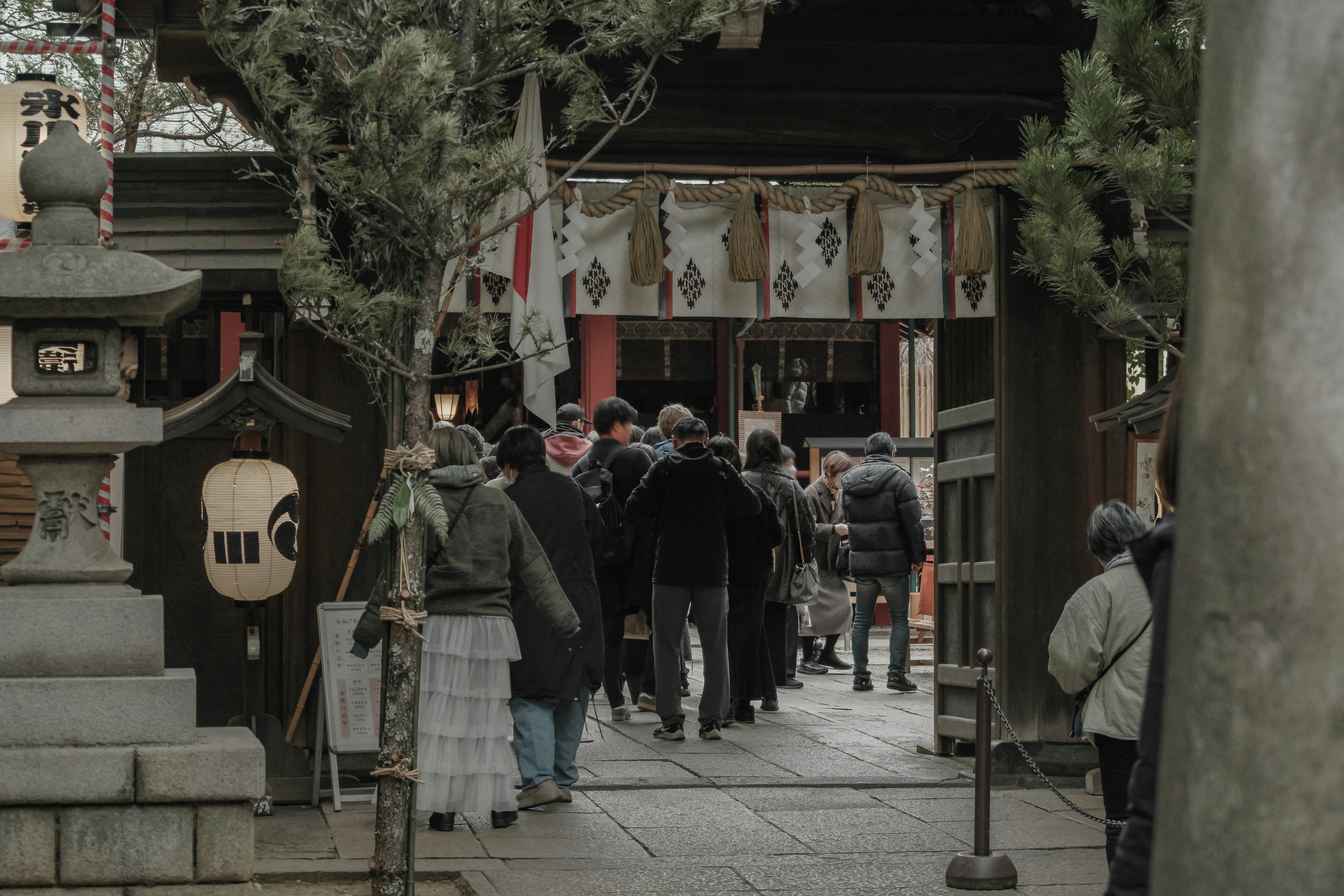 People walking along a shrine path with trees