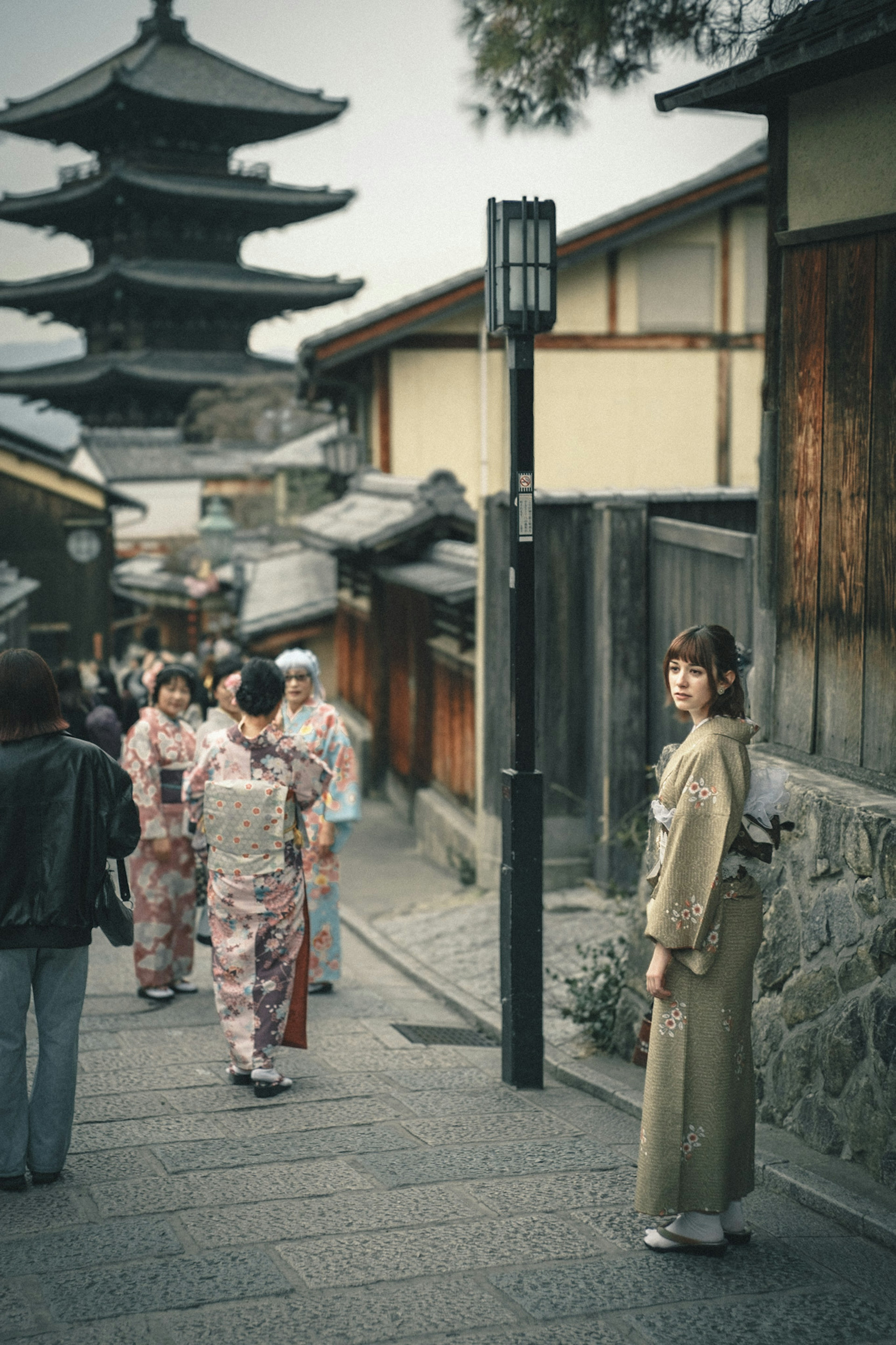 古い街並みの中で立っている着物を着た女性周囲には他の着物姿の人々