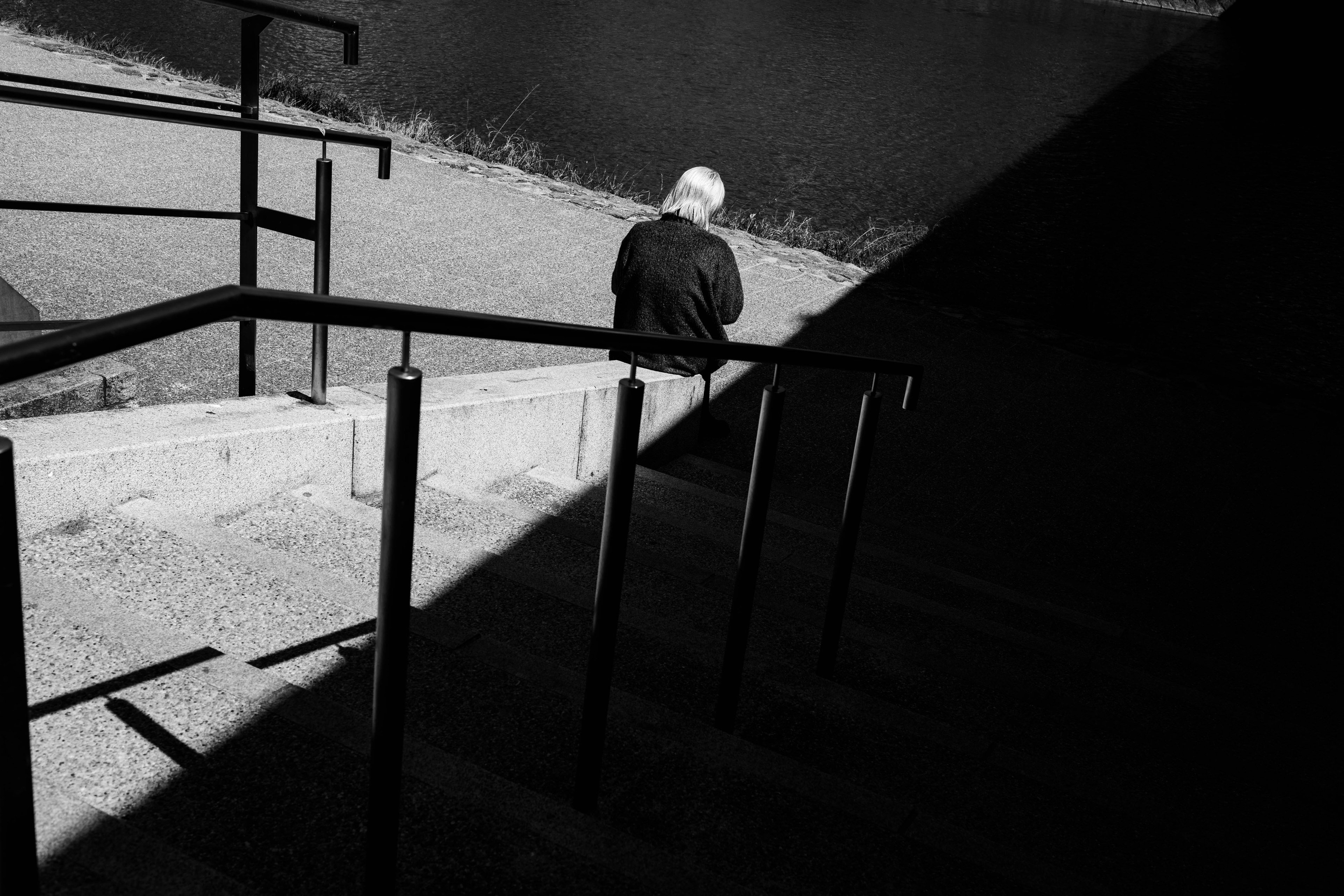 Monochrome photo of an elderly person descending stairs with striking shadows