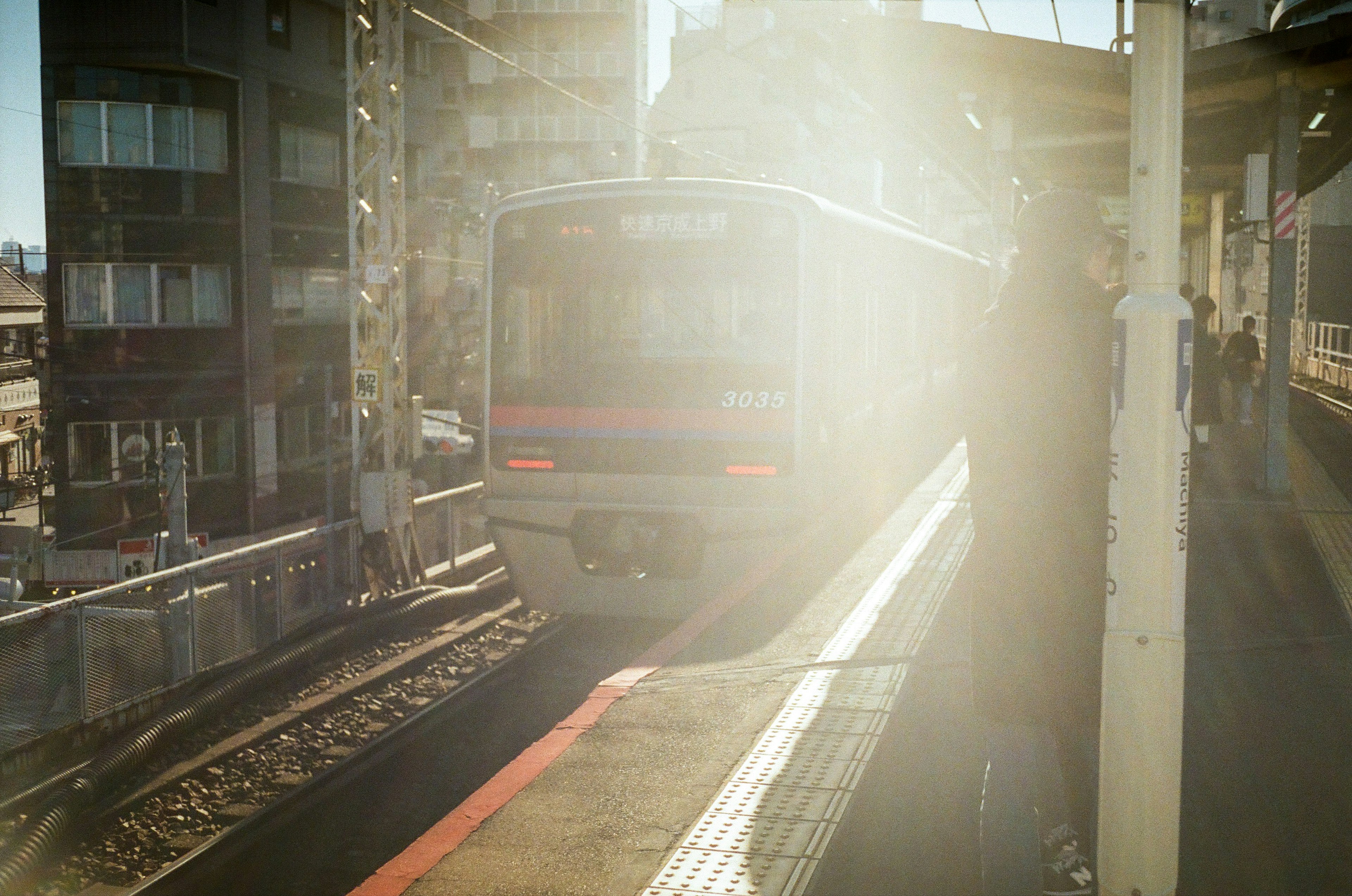 Tren llegando a una estación rodeado de luz brillante y edificios