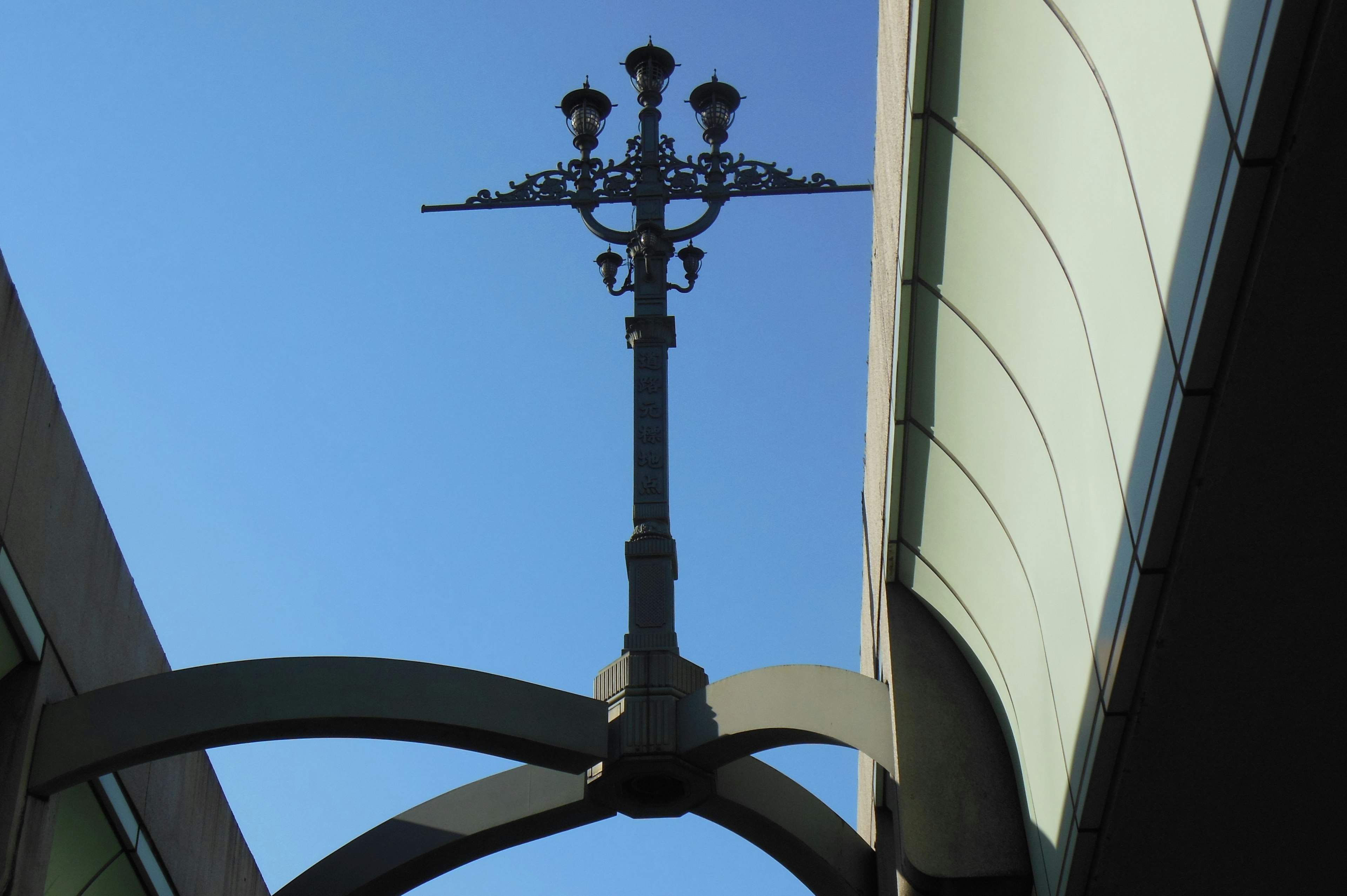 Decorative streetlight pole under blue sky with building structure