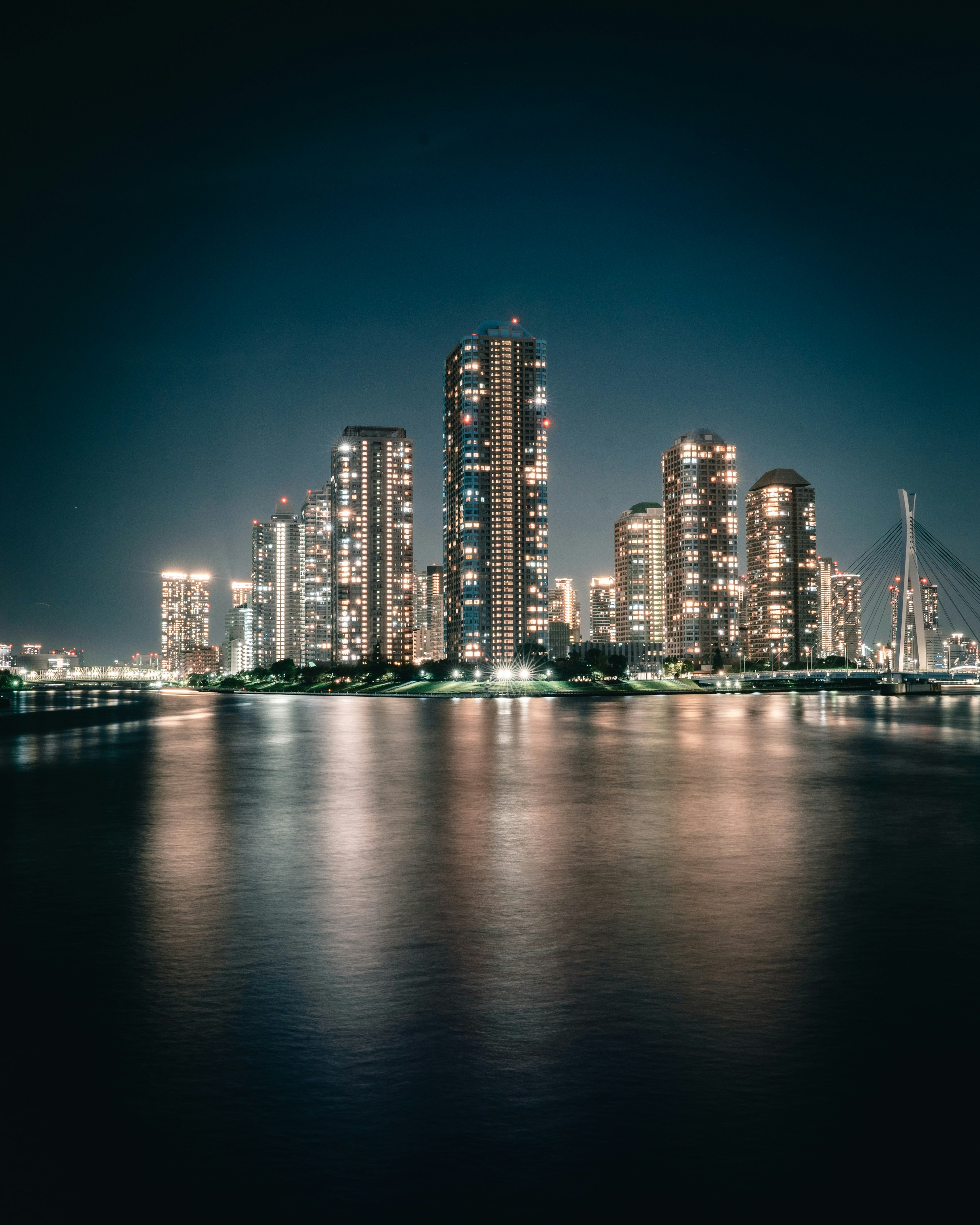 夜间城市景观，灯光照亮的摩天大楼在水面上反射