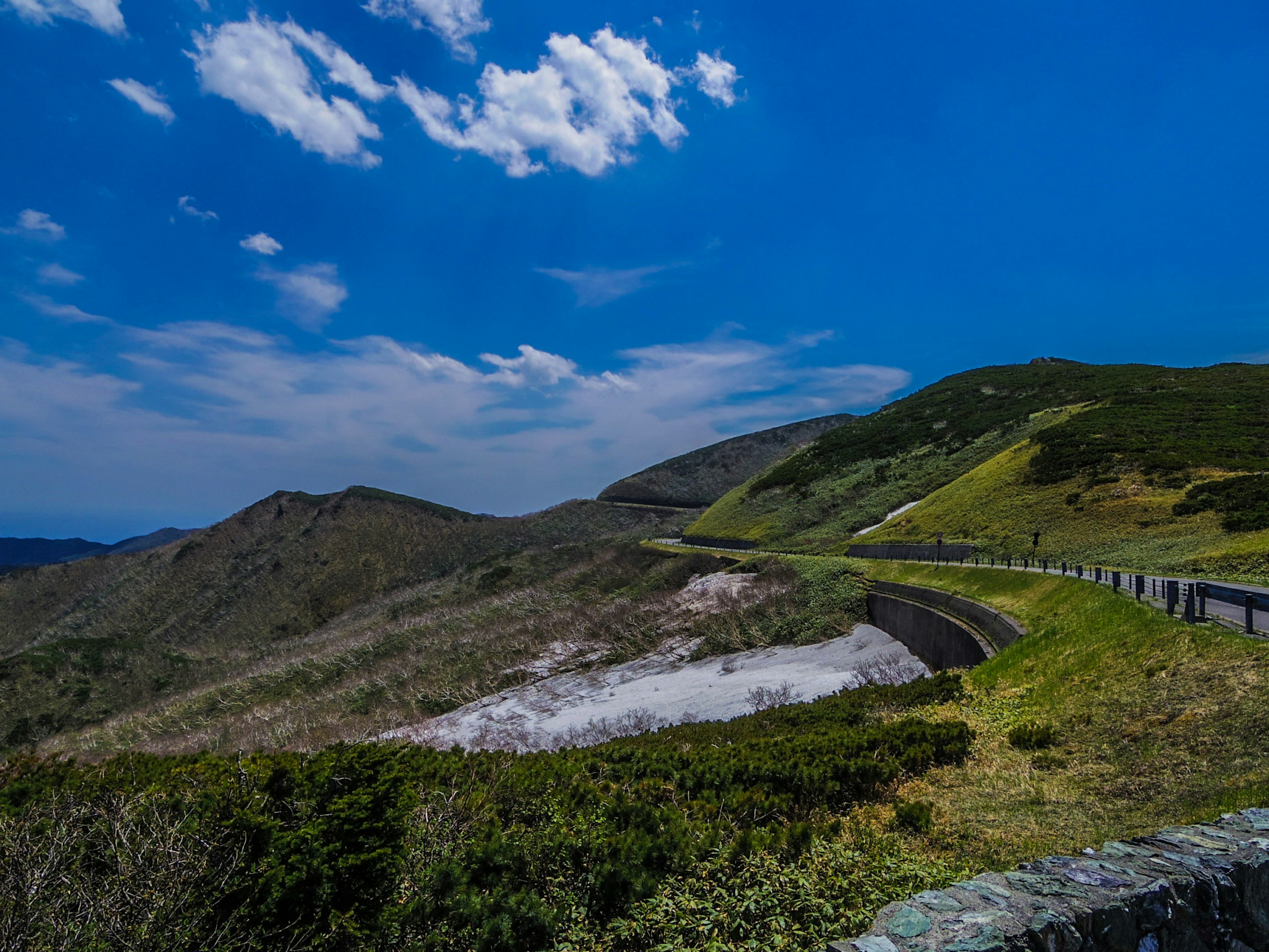 Vue pittoresque de collines verdoyantes sous un ciel bleu avec une route sinueuse