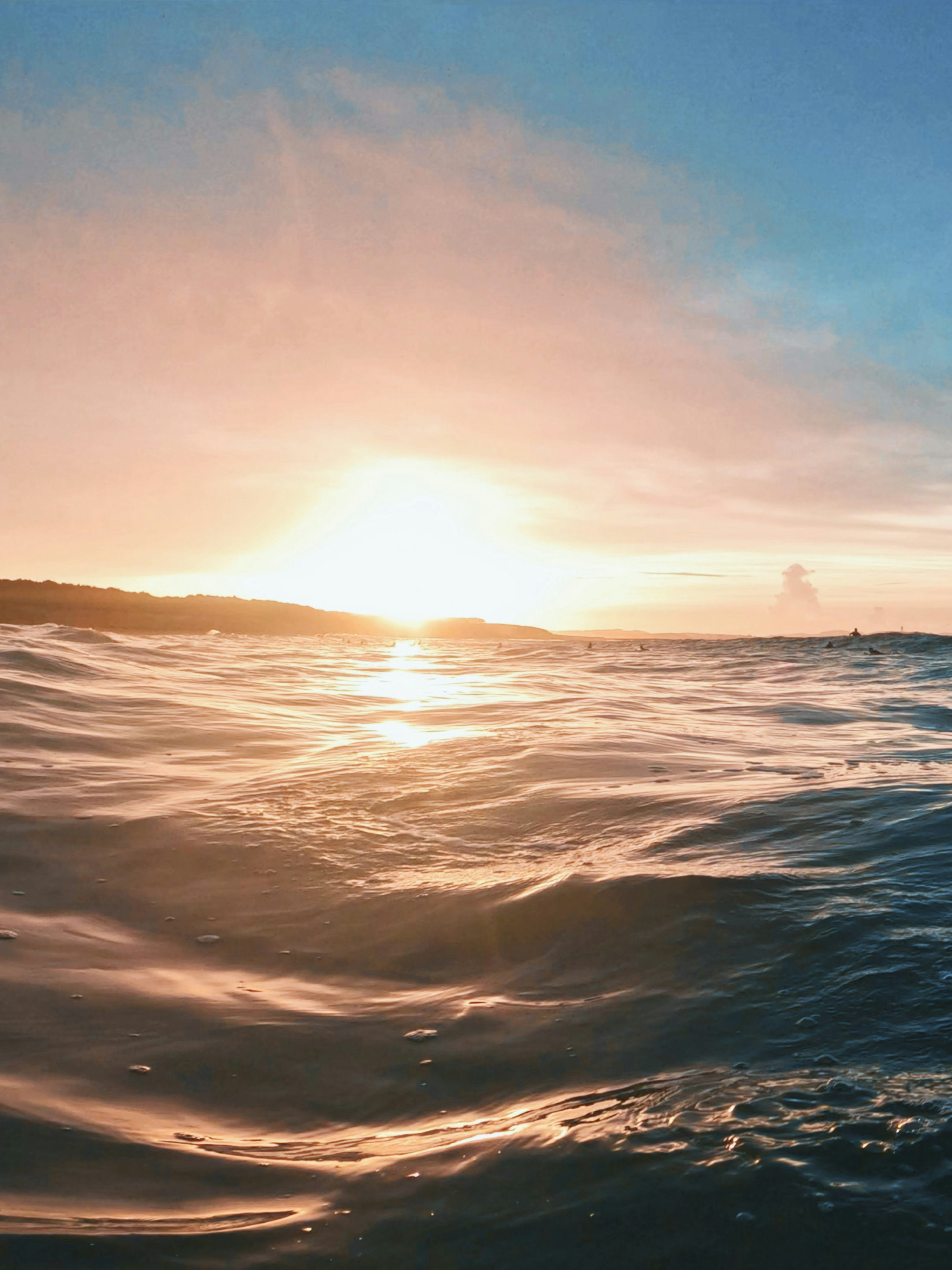 Calm ocean waves reflecting the light of a sunset