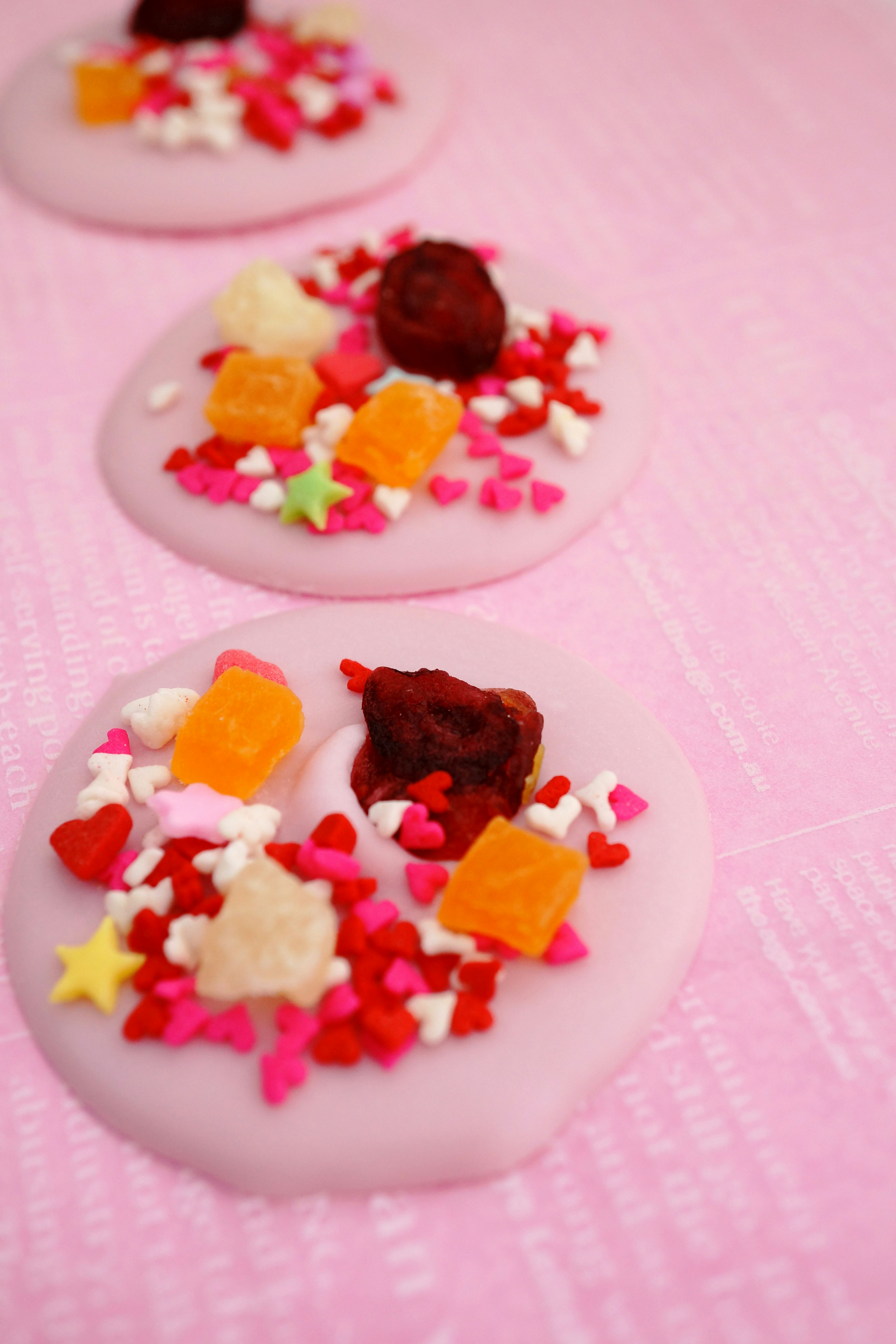 Colorful toppings on sweet treats against a pink background