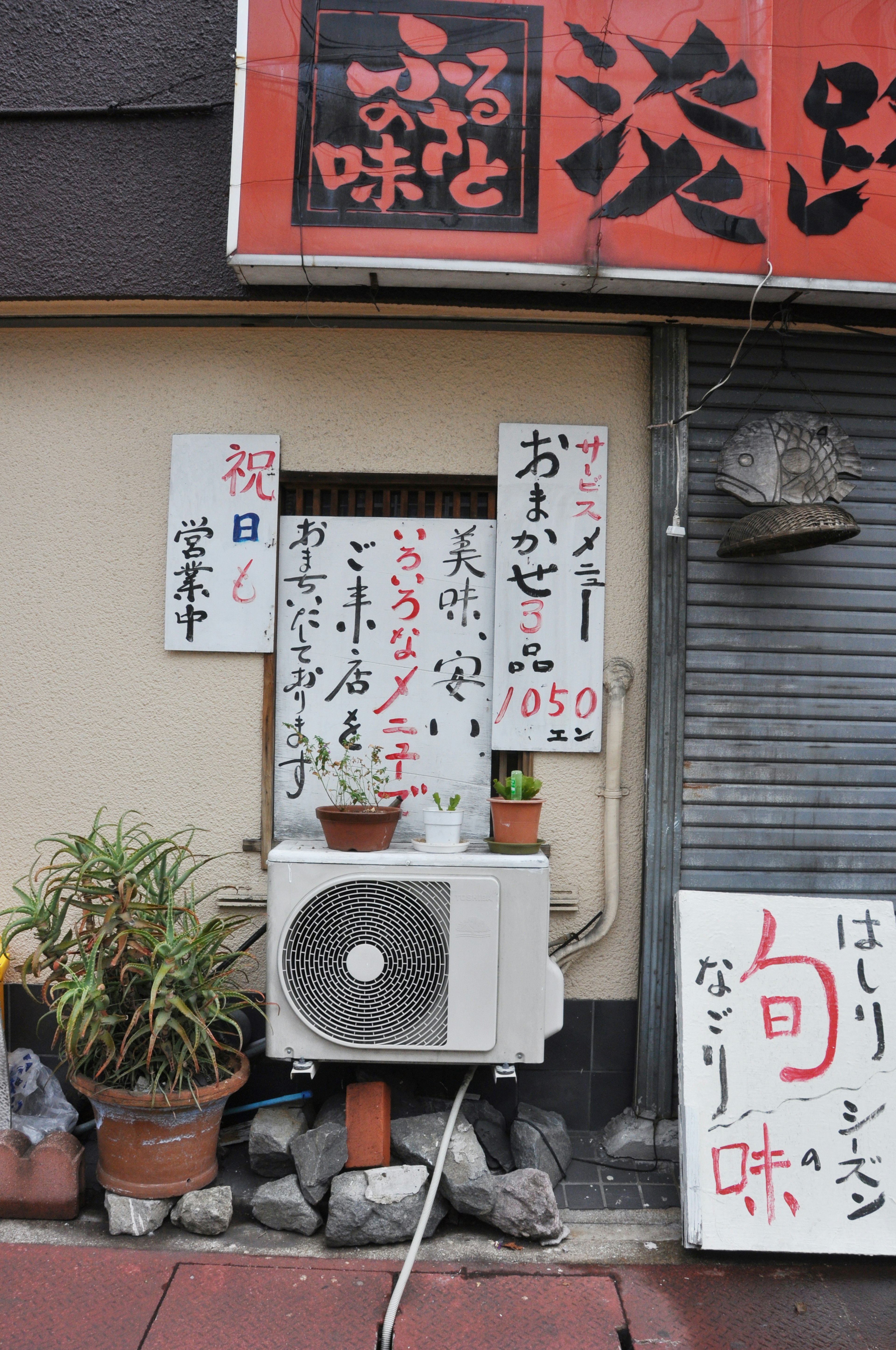 Exterior of a restaurant featuring displayed menus and an air conditioner