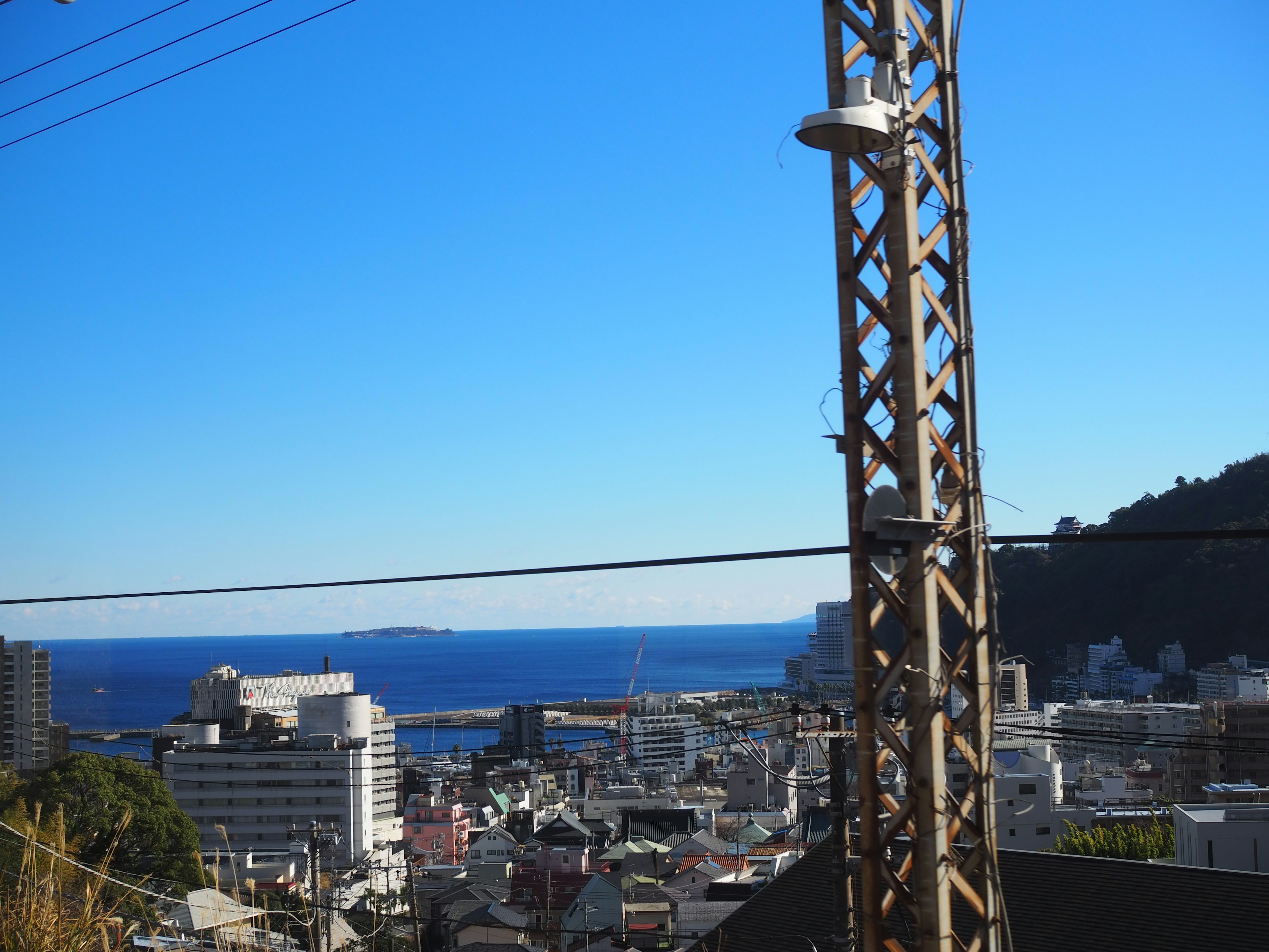 View of the ocean and city with a utility pole under a blue sky