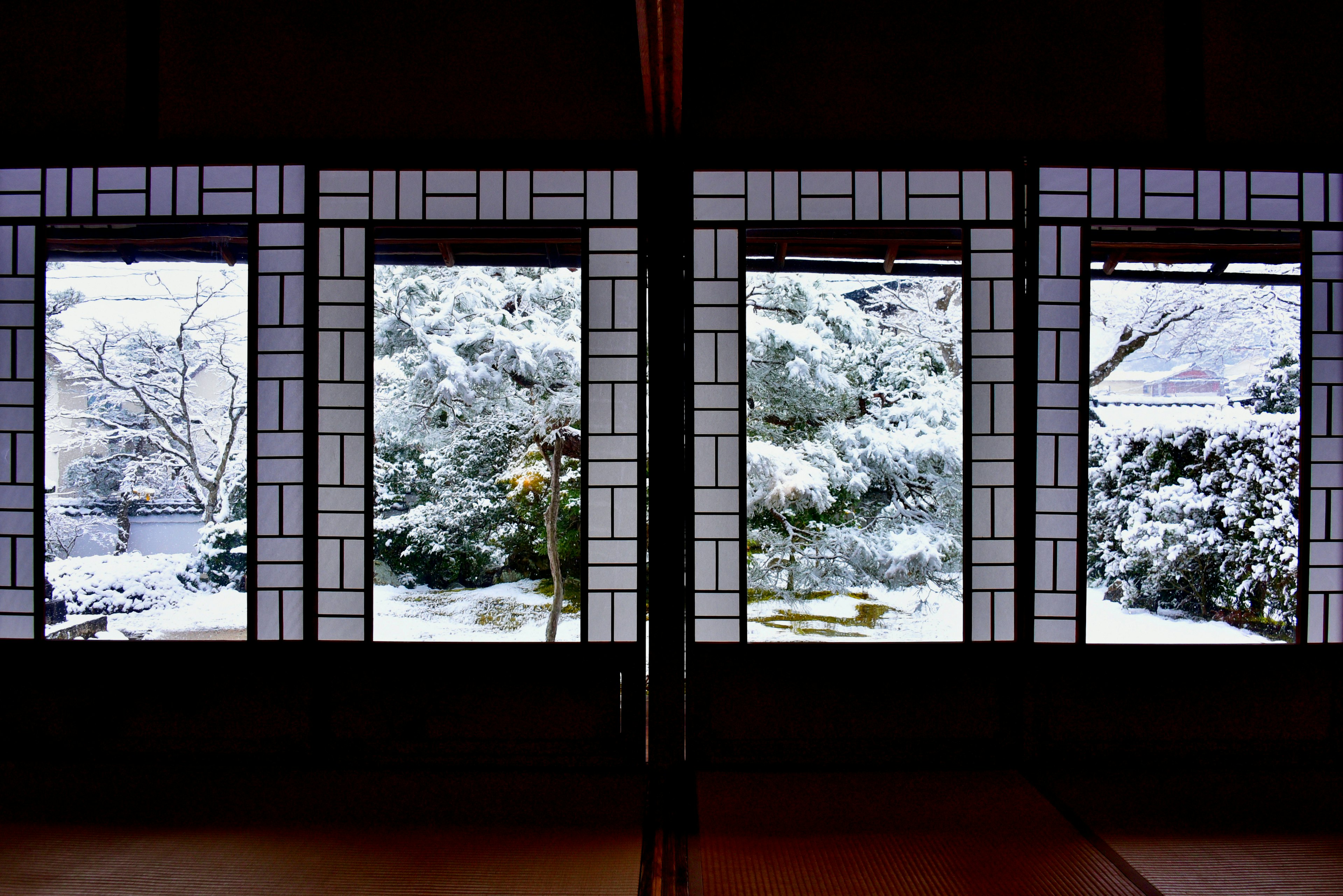 Traditional Japanese windows overlooking a snow-covered garden