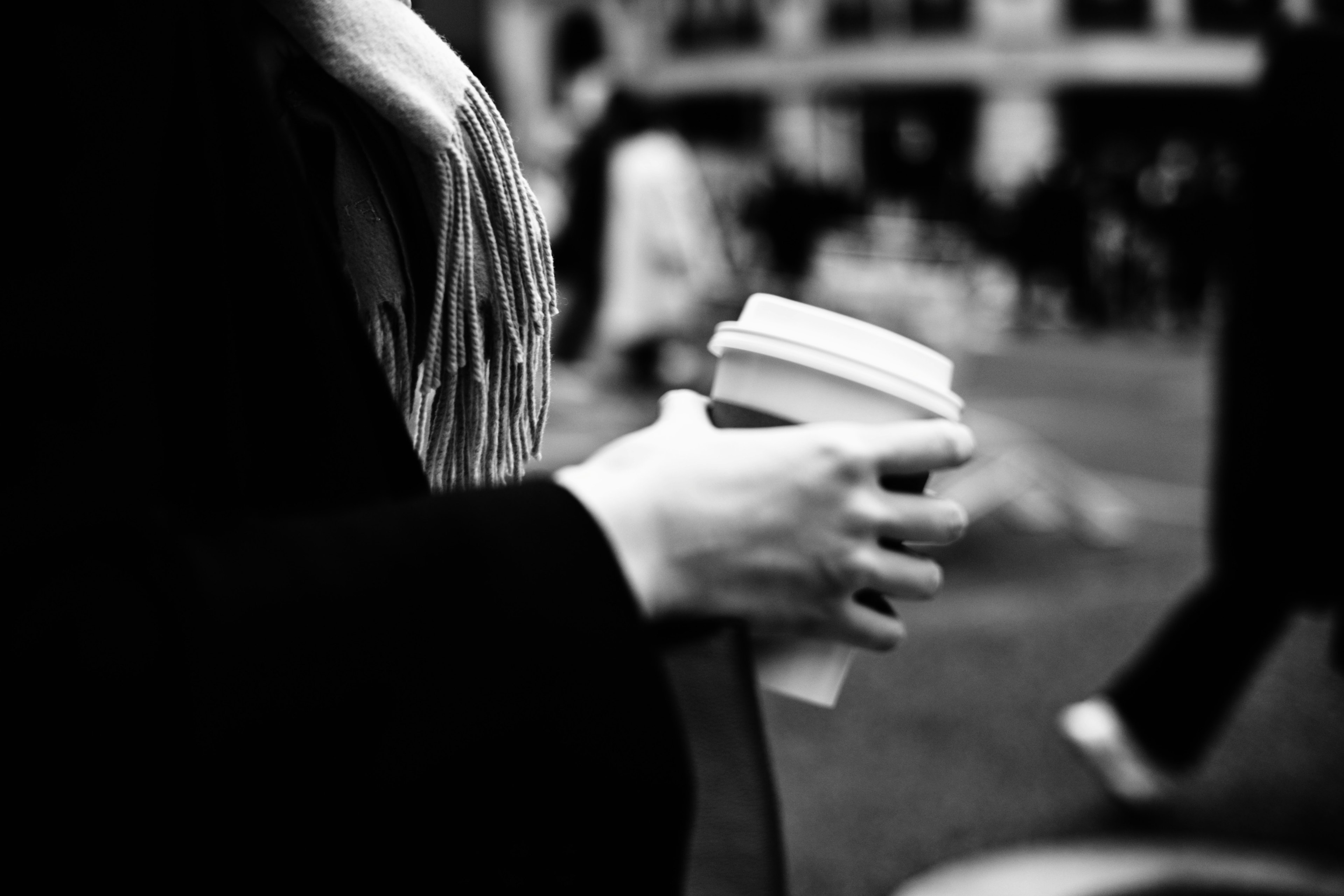 Black and white photo of a woman's hand holding a coffee cup