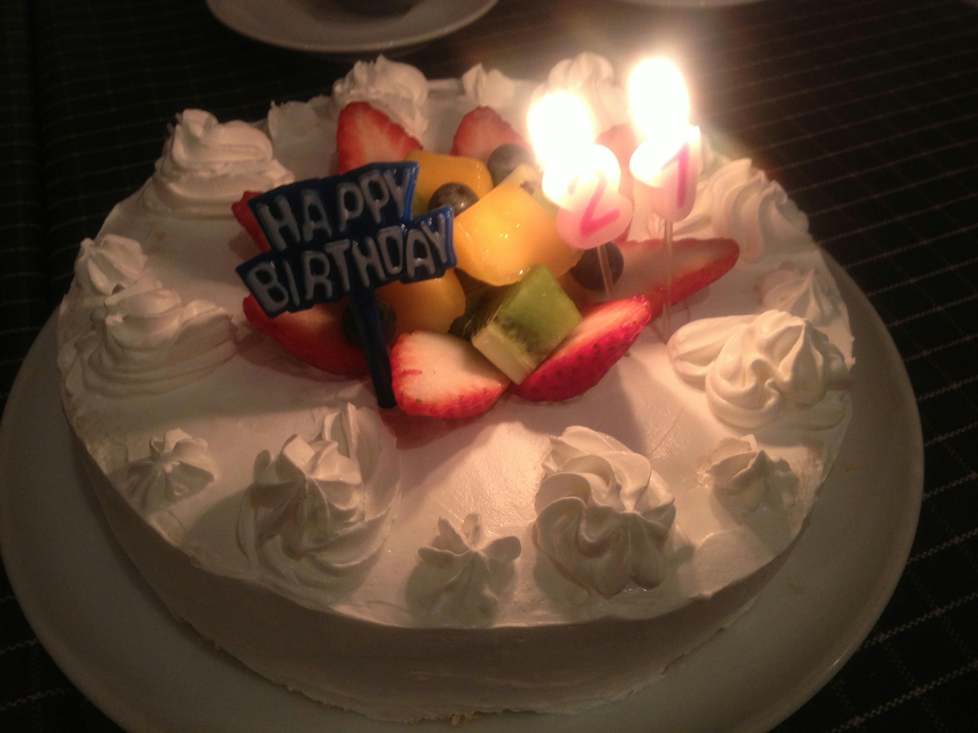 Pastel de cumpleaños con velas y cobertura de frutas