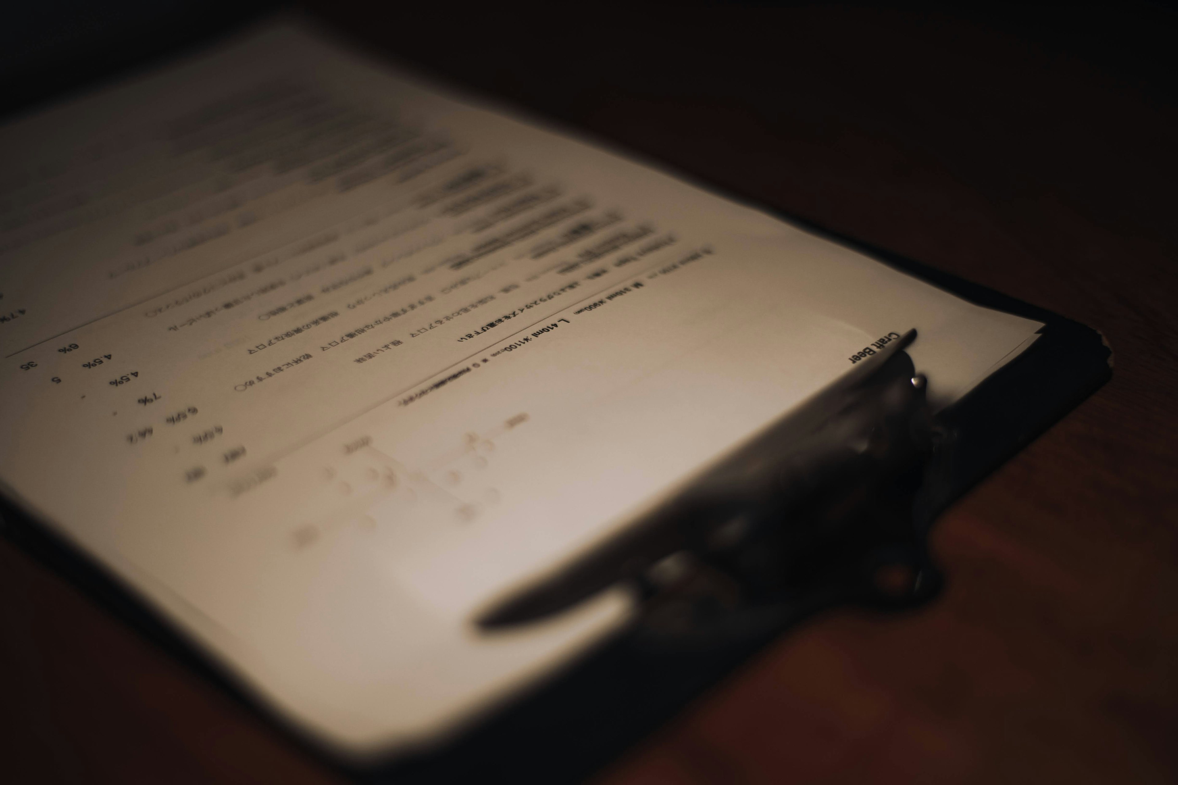 A menu page placed on a clipboard captured in a dimly lit environment