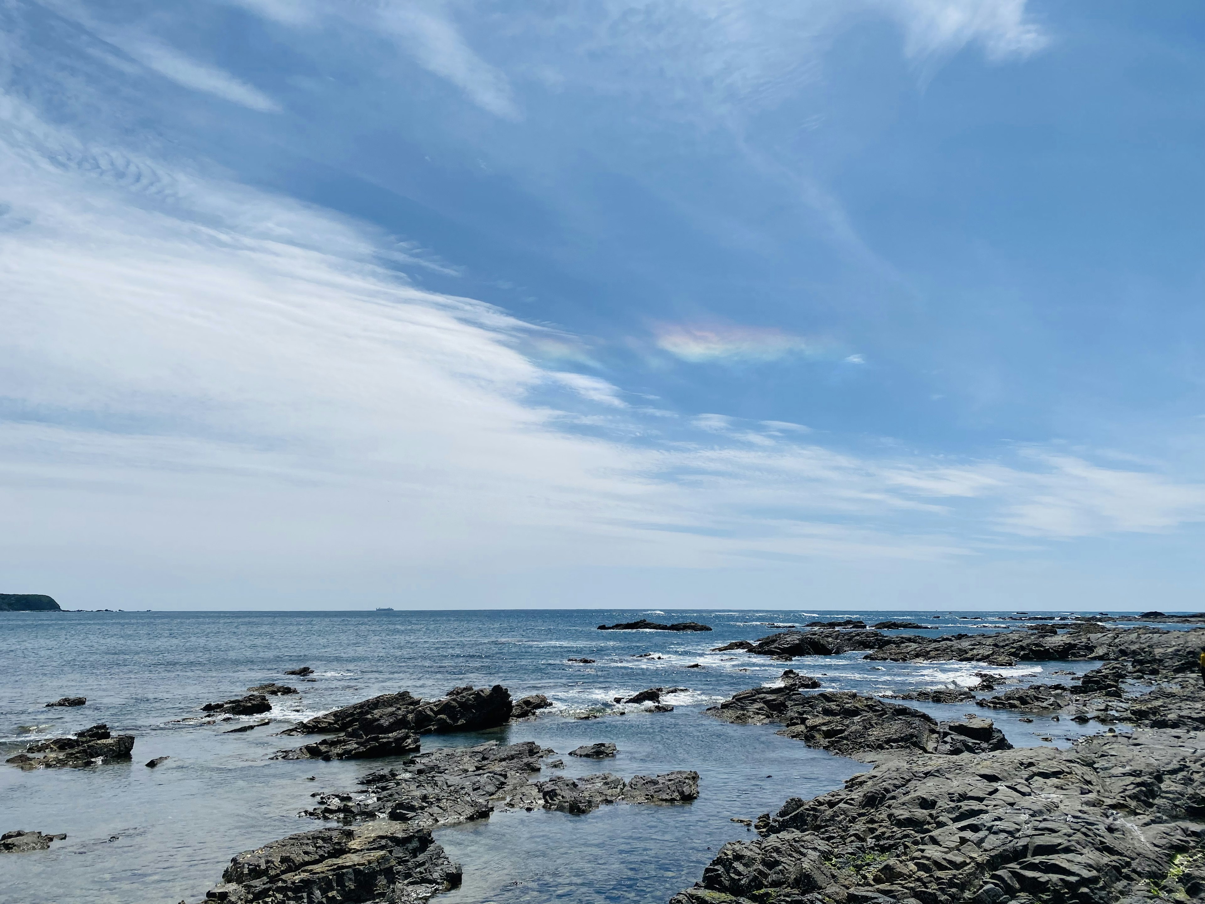 青い空と海に囲まれた岩だらけの海岸の景色