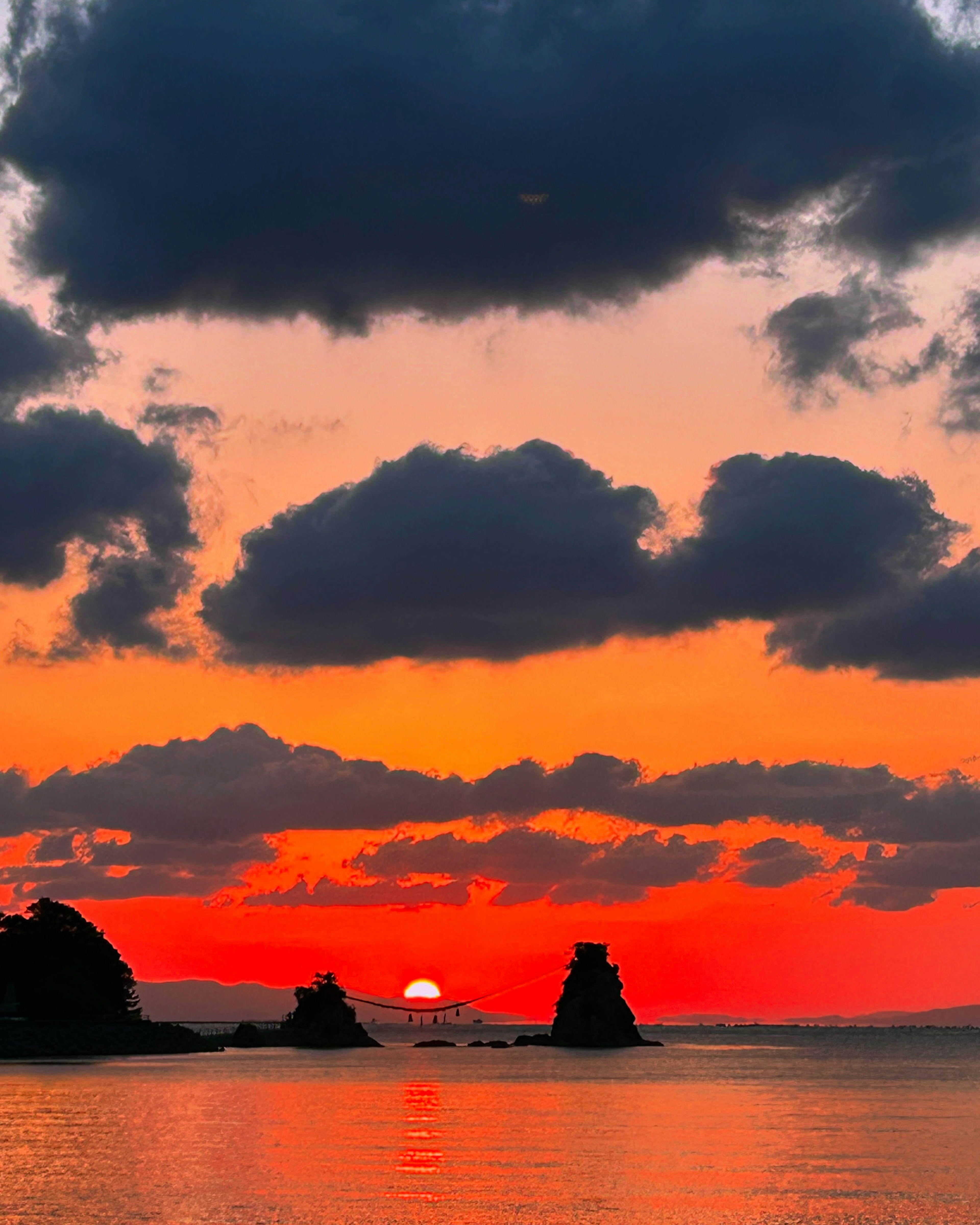 Paisaje marino con atardecer y formaciones rocosas oscuras