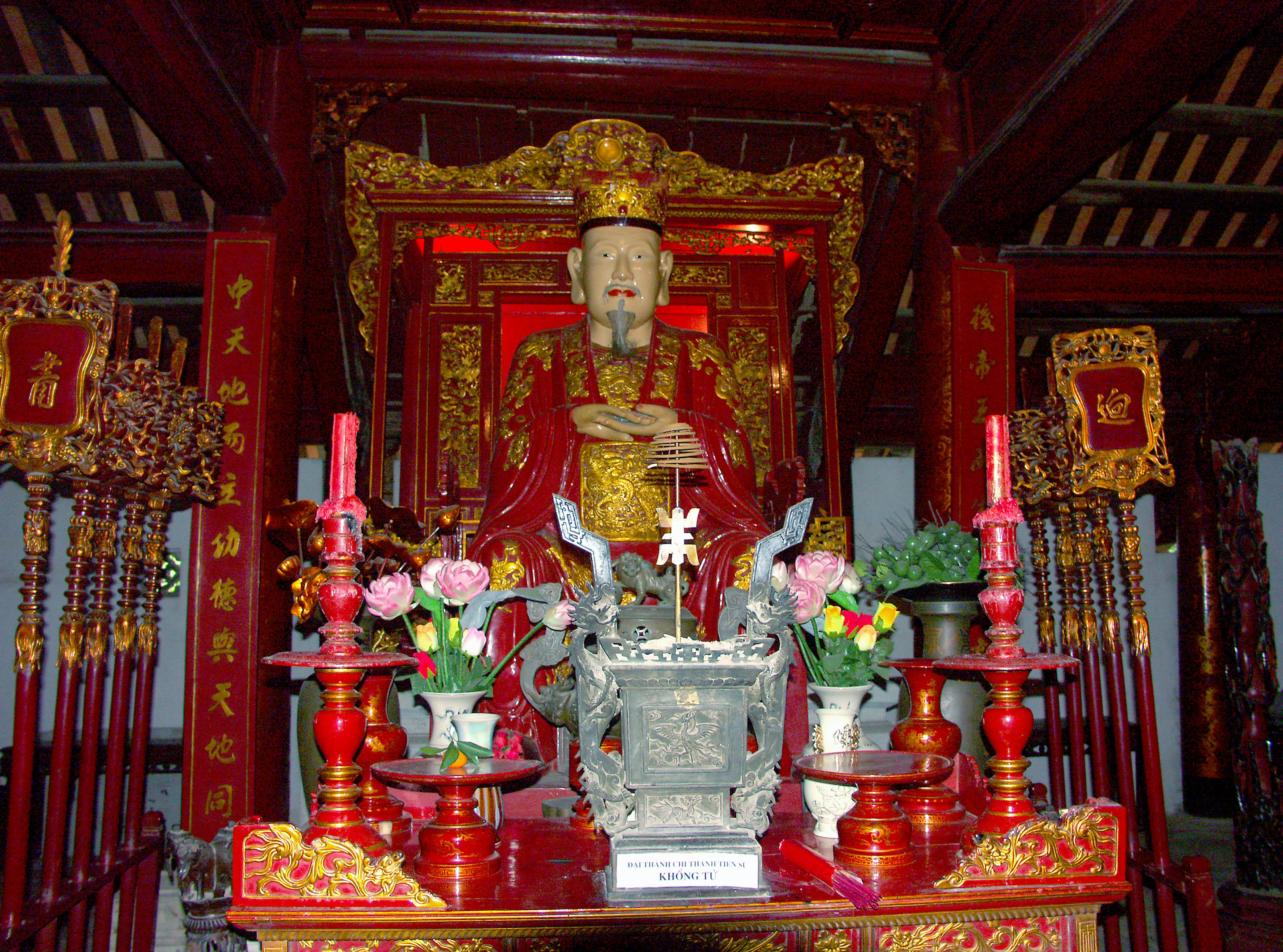 Una estatua de deidad decorada en rojo y oro se encuentra en un altar