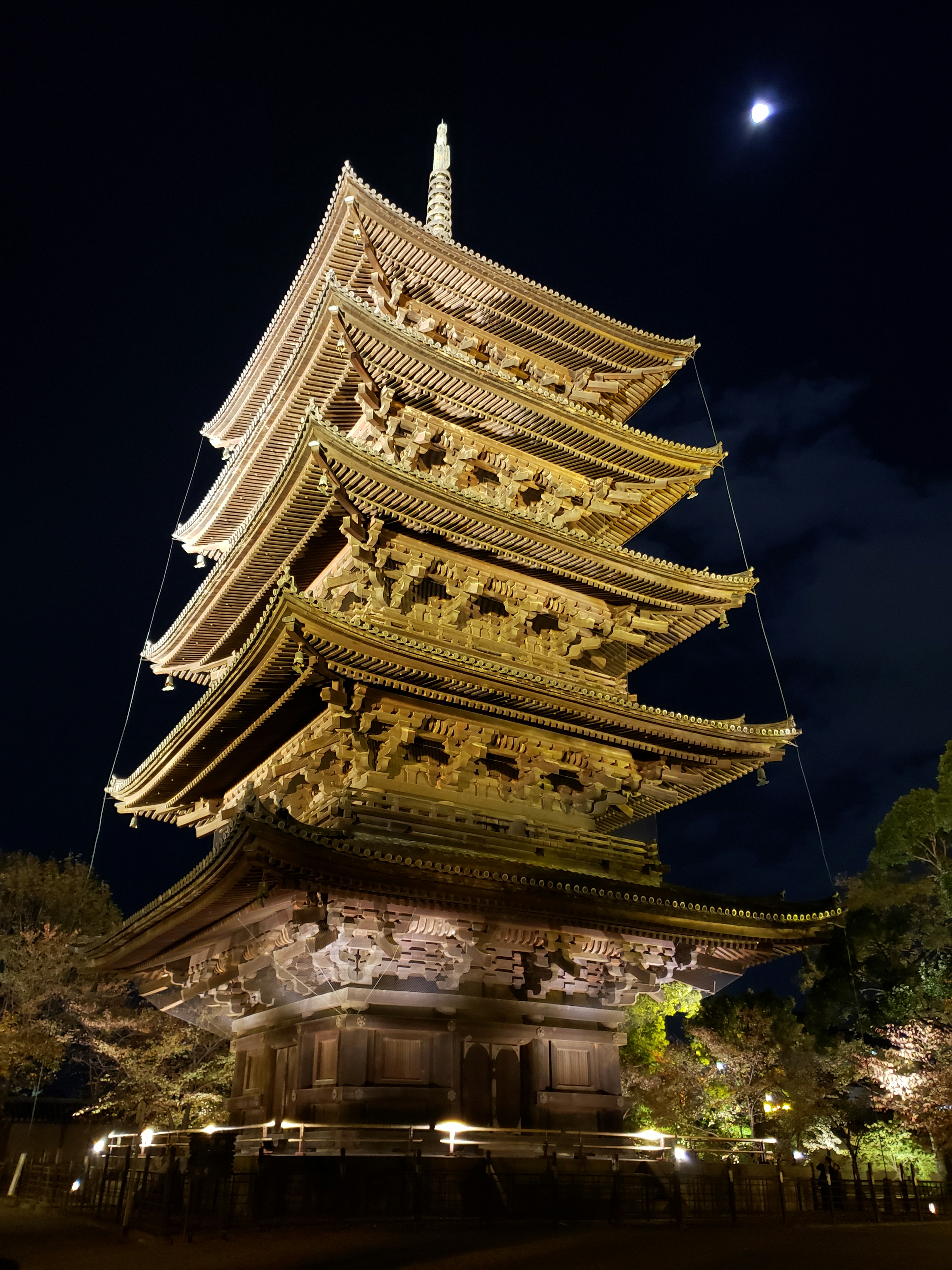 Illuminated five-story pagoda at night with moonlight