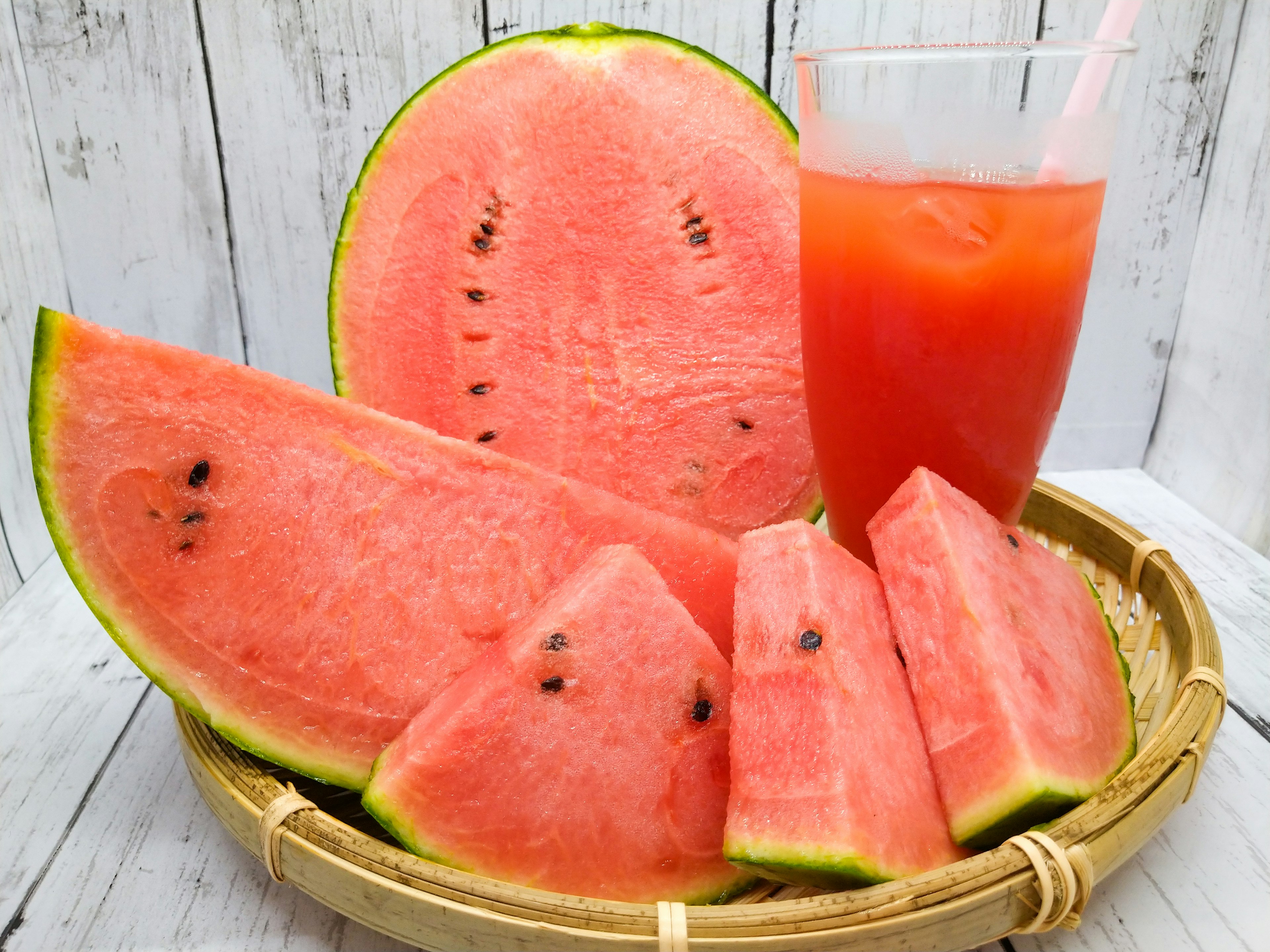 Sliced watermelon and a glass of watermelon juice in a basket