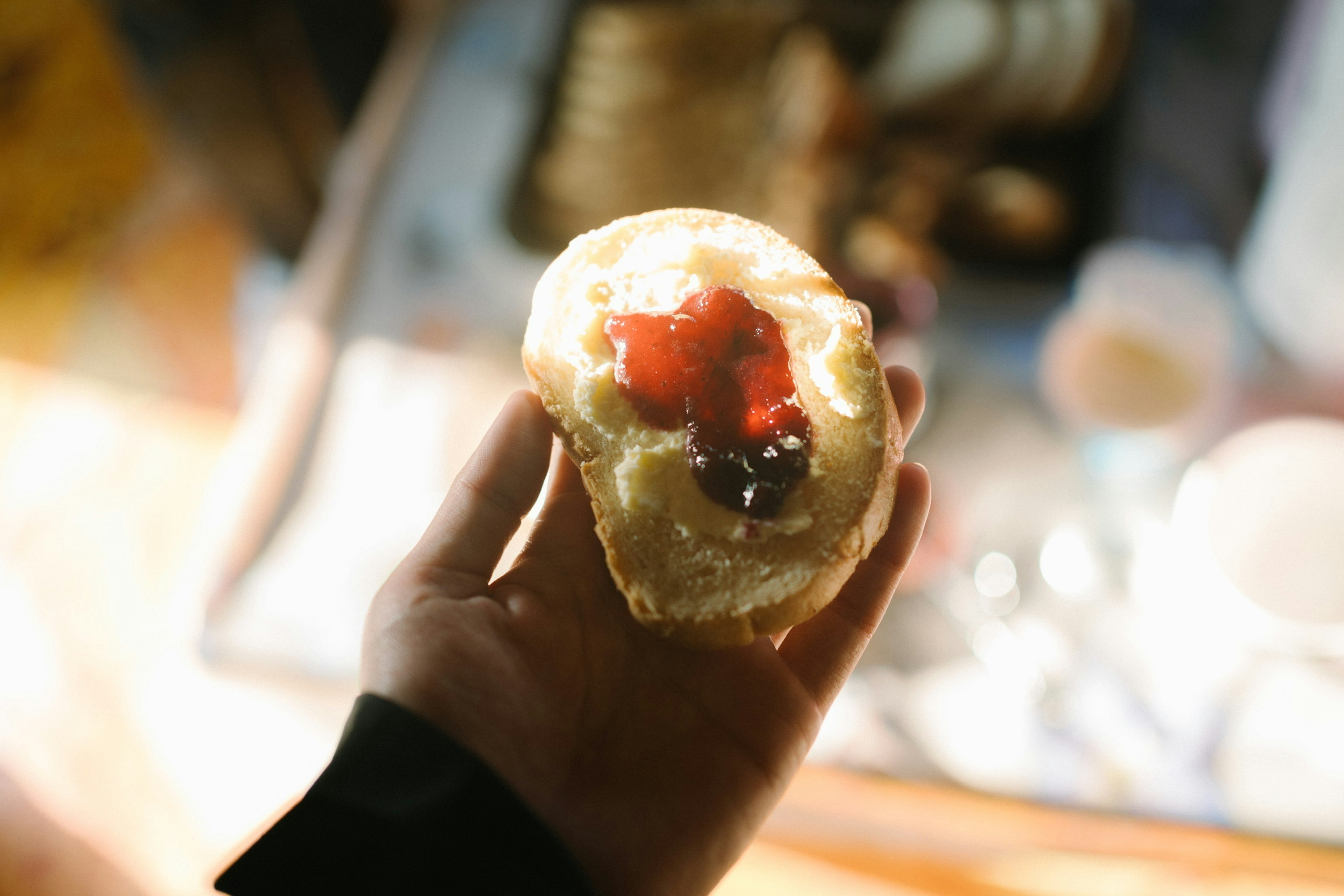 Nahaufnahme eines mit Marmelade gefüllten Gebäcks, das in der Hand gehalten wird