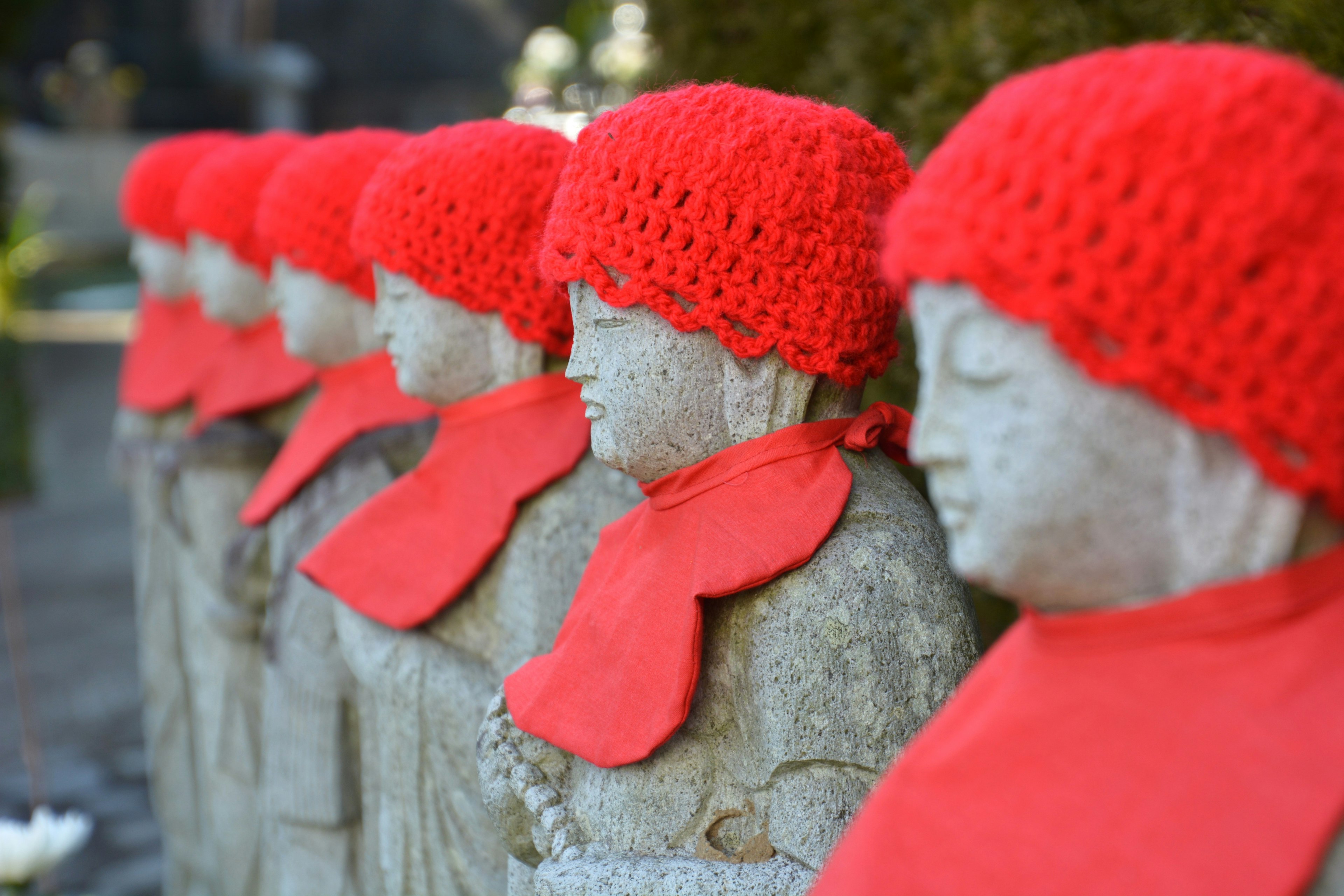 Row of stone statues wearing red hats and scarves