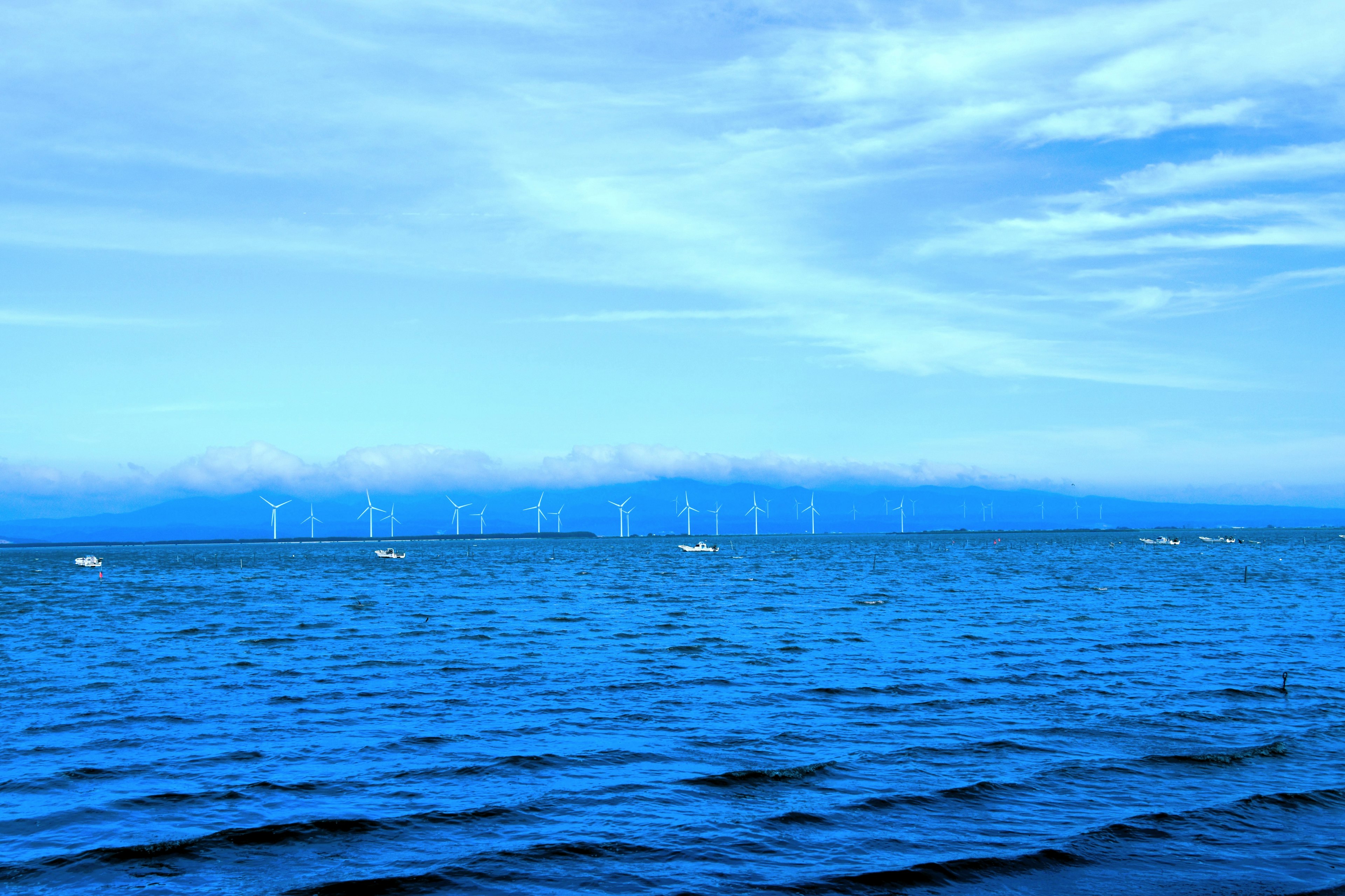 Vista panoramica di un oceano blu con turbine eoliche in lontananza