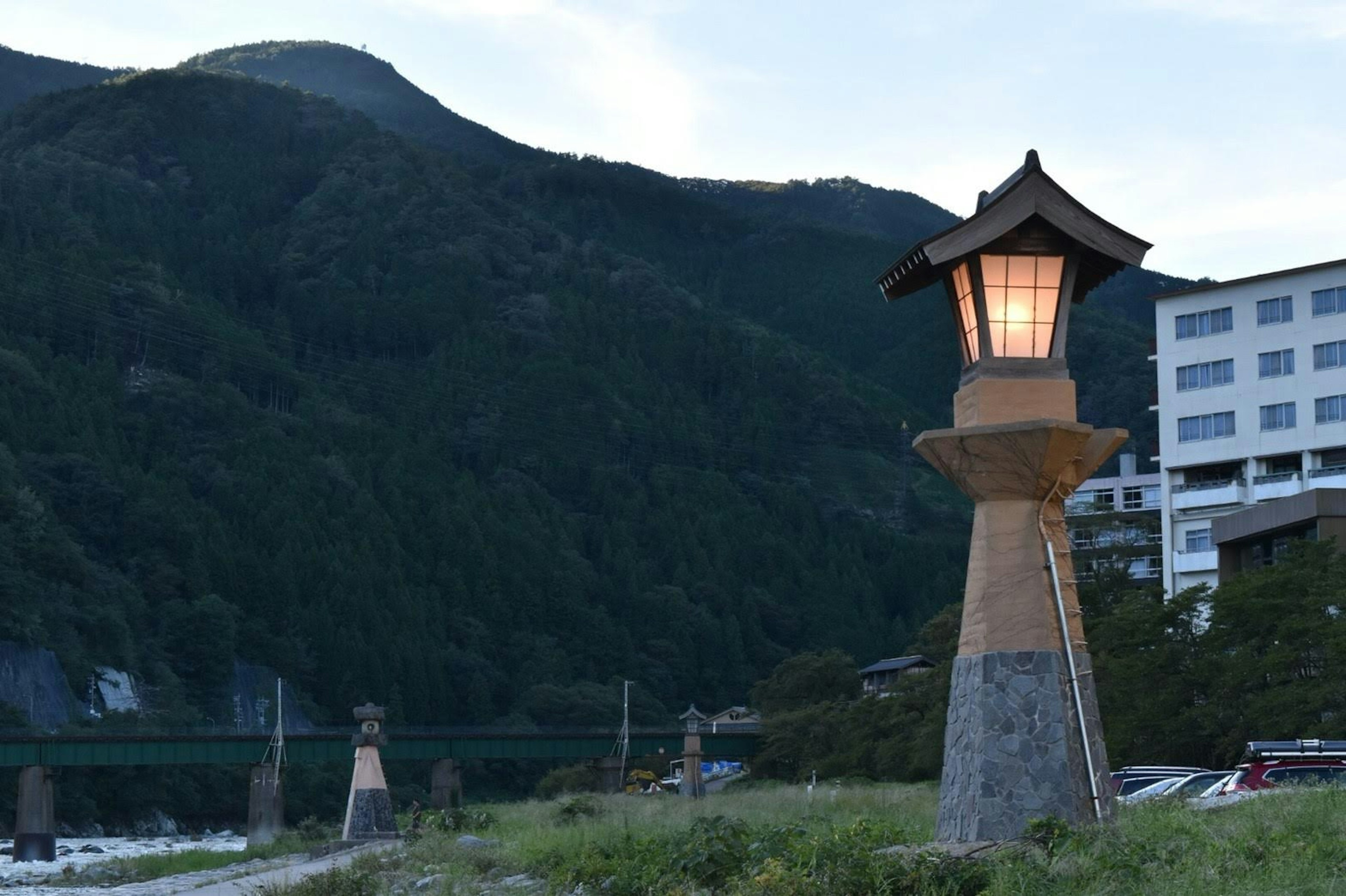 Traditional lantern standing with mountains in the background and modern building