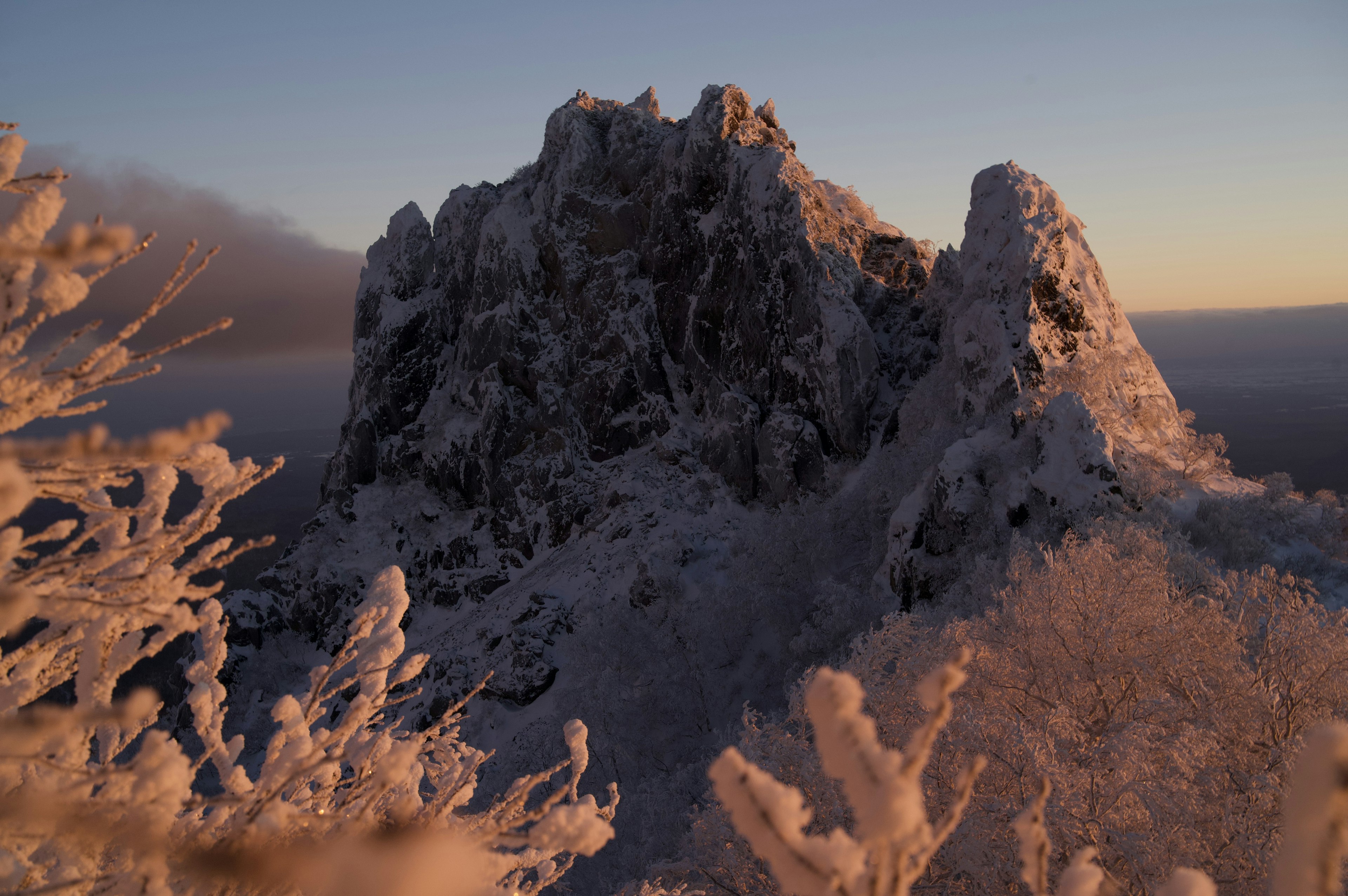 Snow-covered mountain peak with frost and misty landscape