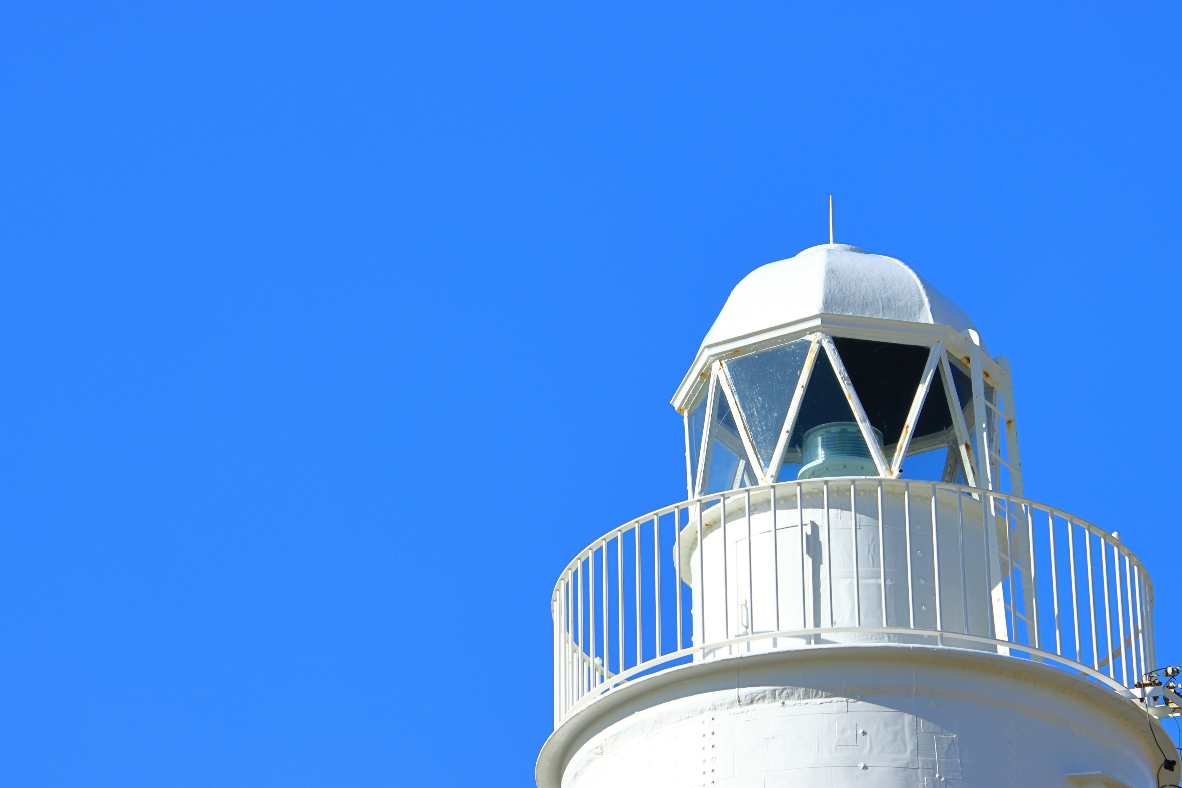 Top of a white lighthouse against a blue sky