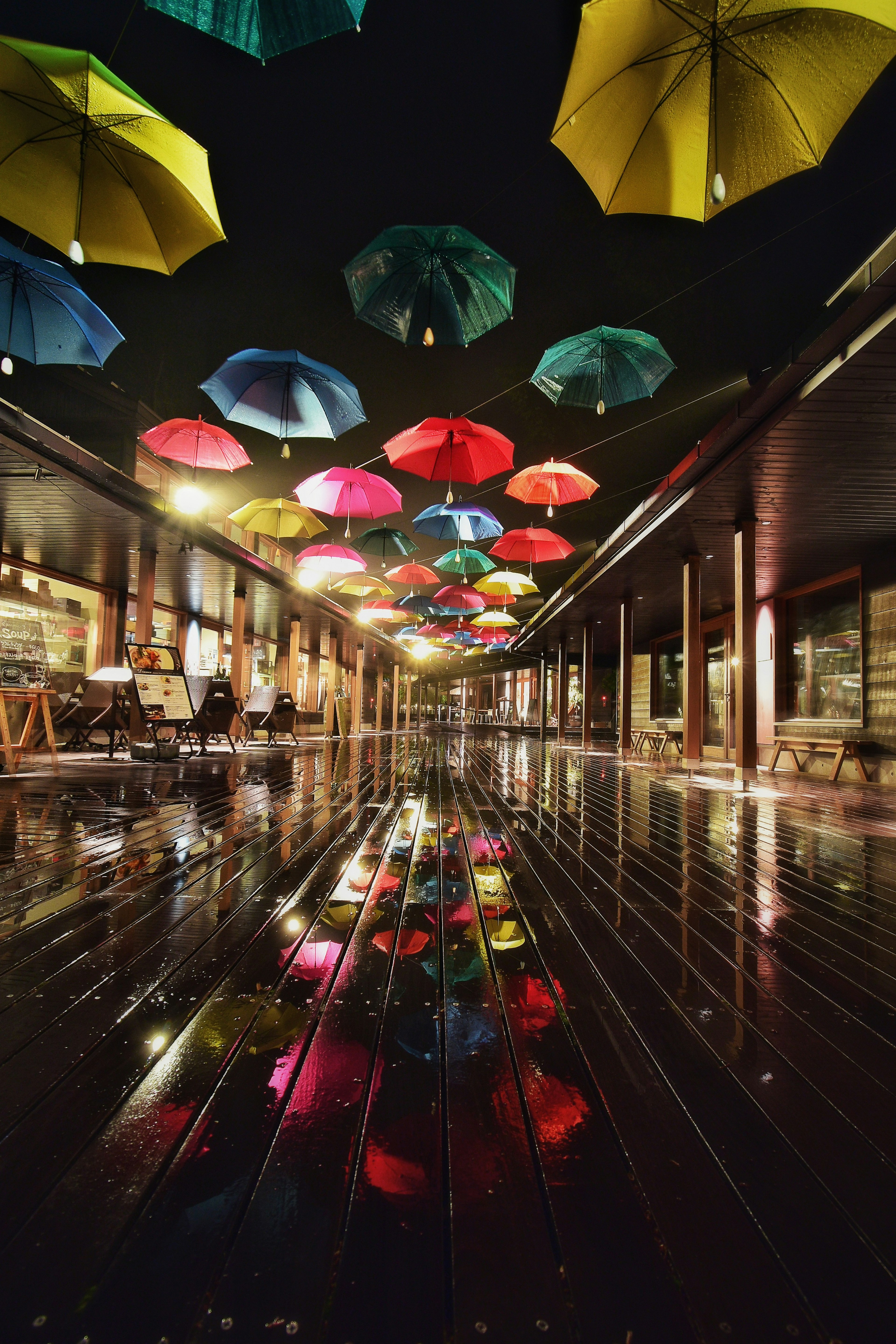 Colorful umbrellas suspended in an indoor space with reflective wooden floor