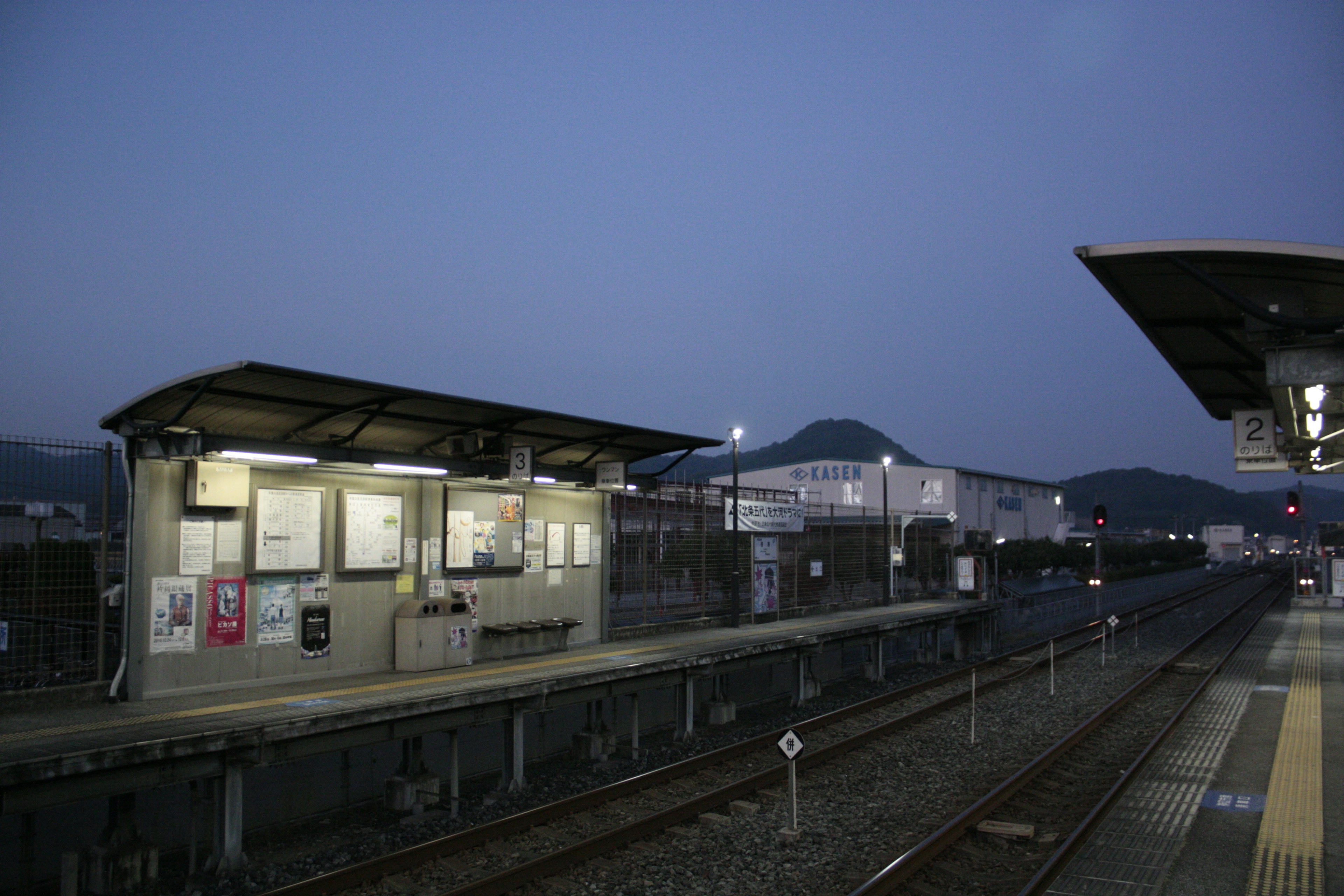 薄明かりの中の静かな駅のプラットフォームと建物