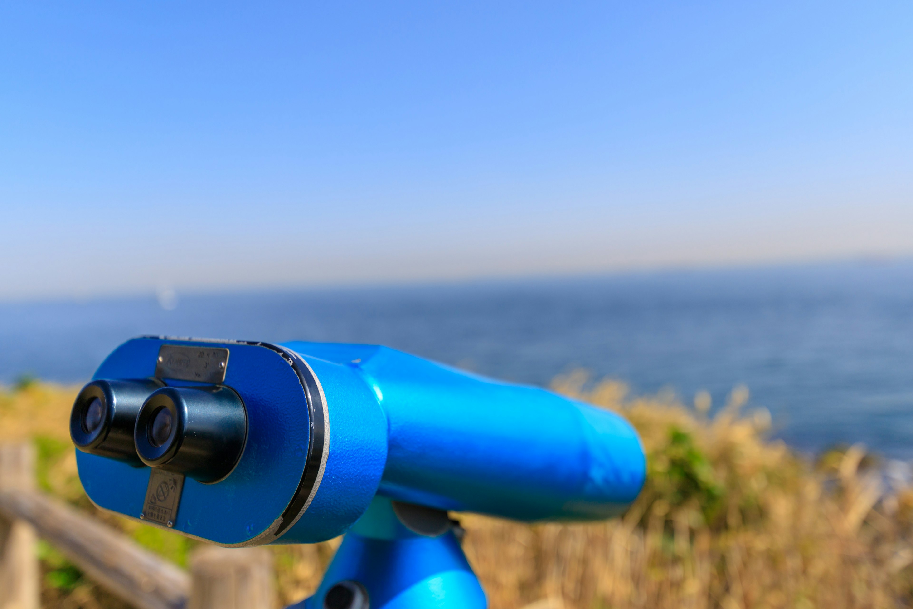 Teleskop biru menghadap ke laut di bawah langit cerah