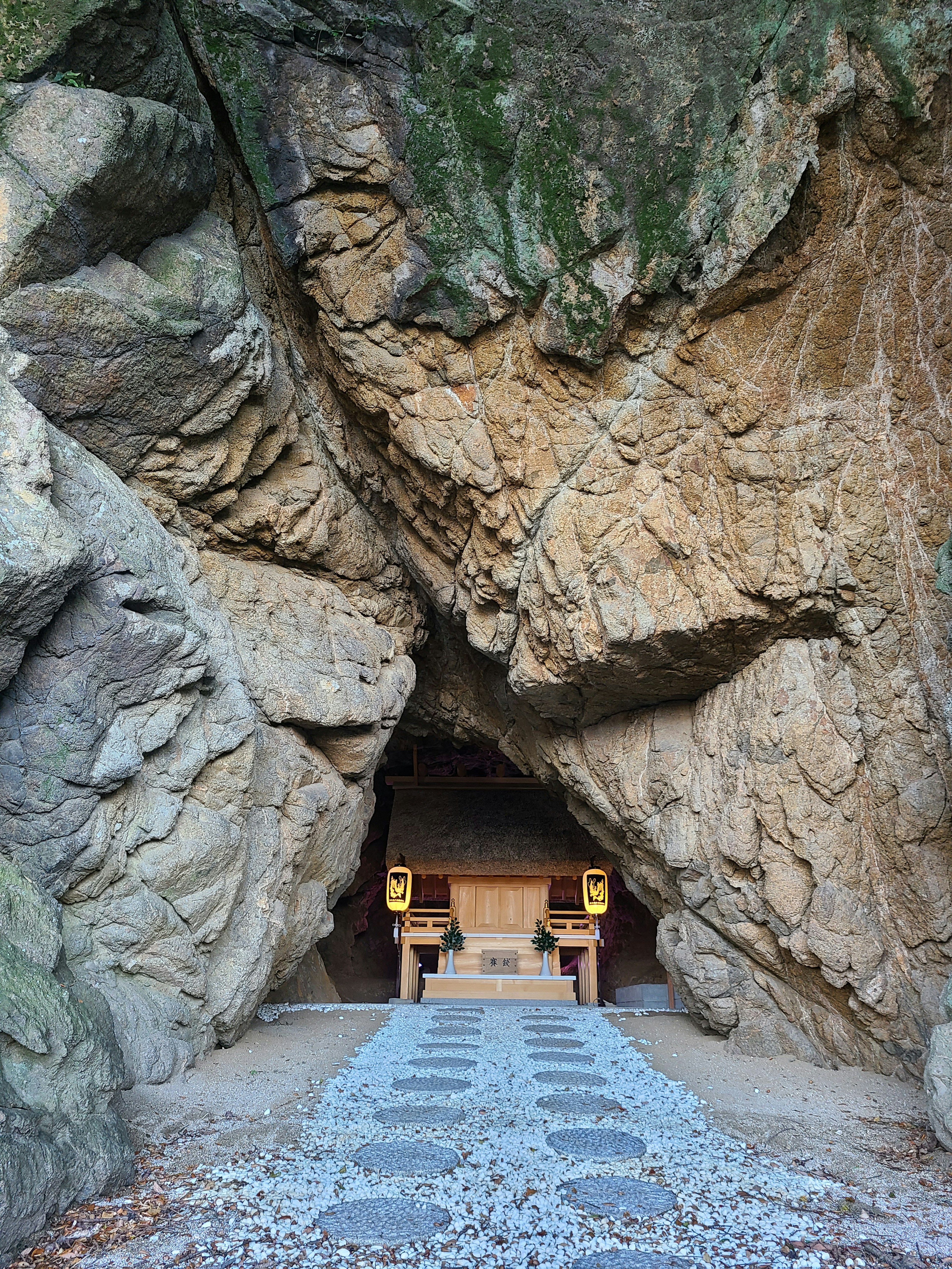 Entrata di un santuario incassato tra le rocce con un sentiero di pietra