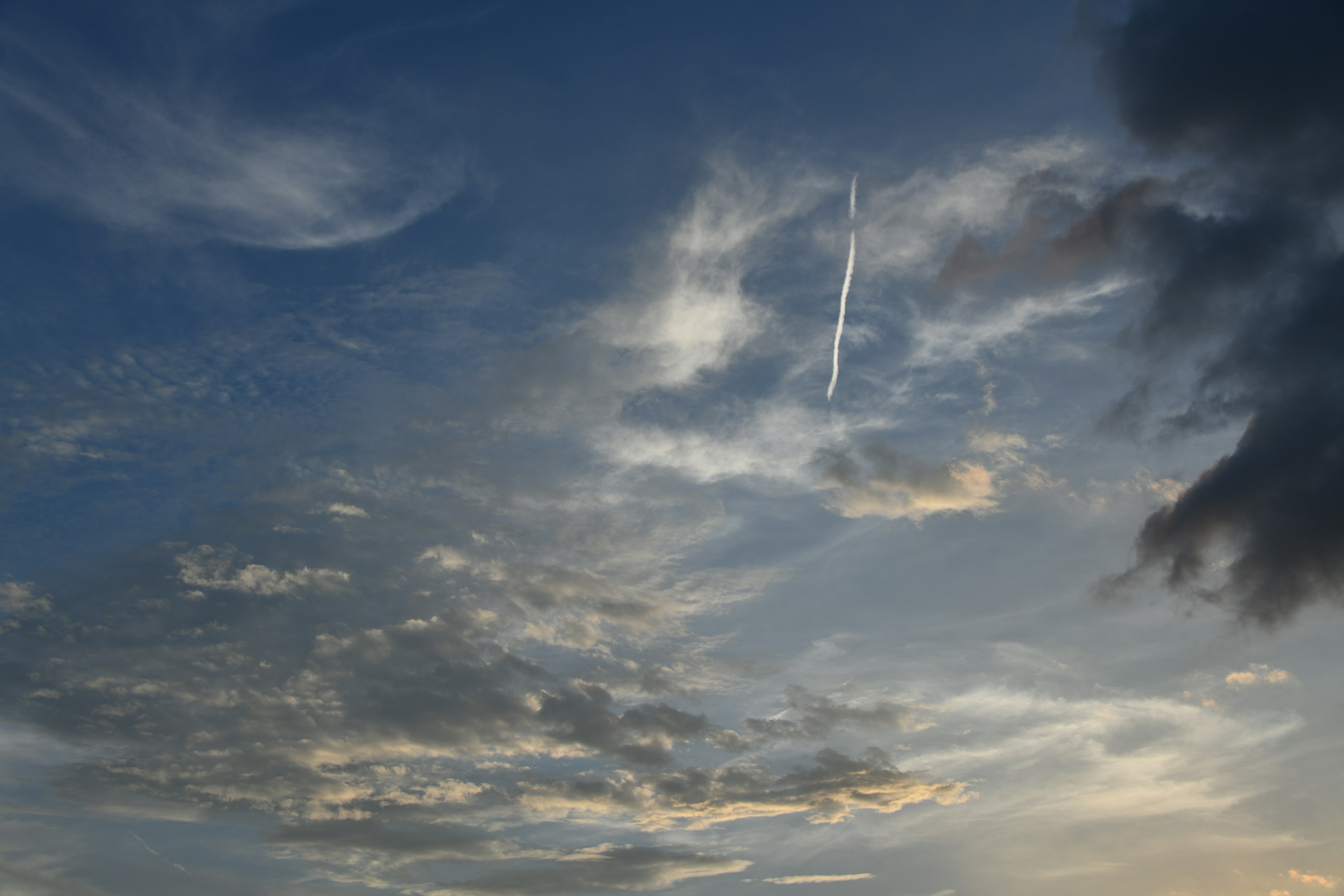 Una vista panoramica del cielo blu con nuvole e una scia di aereo