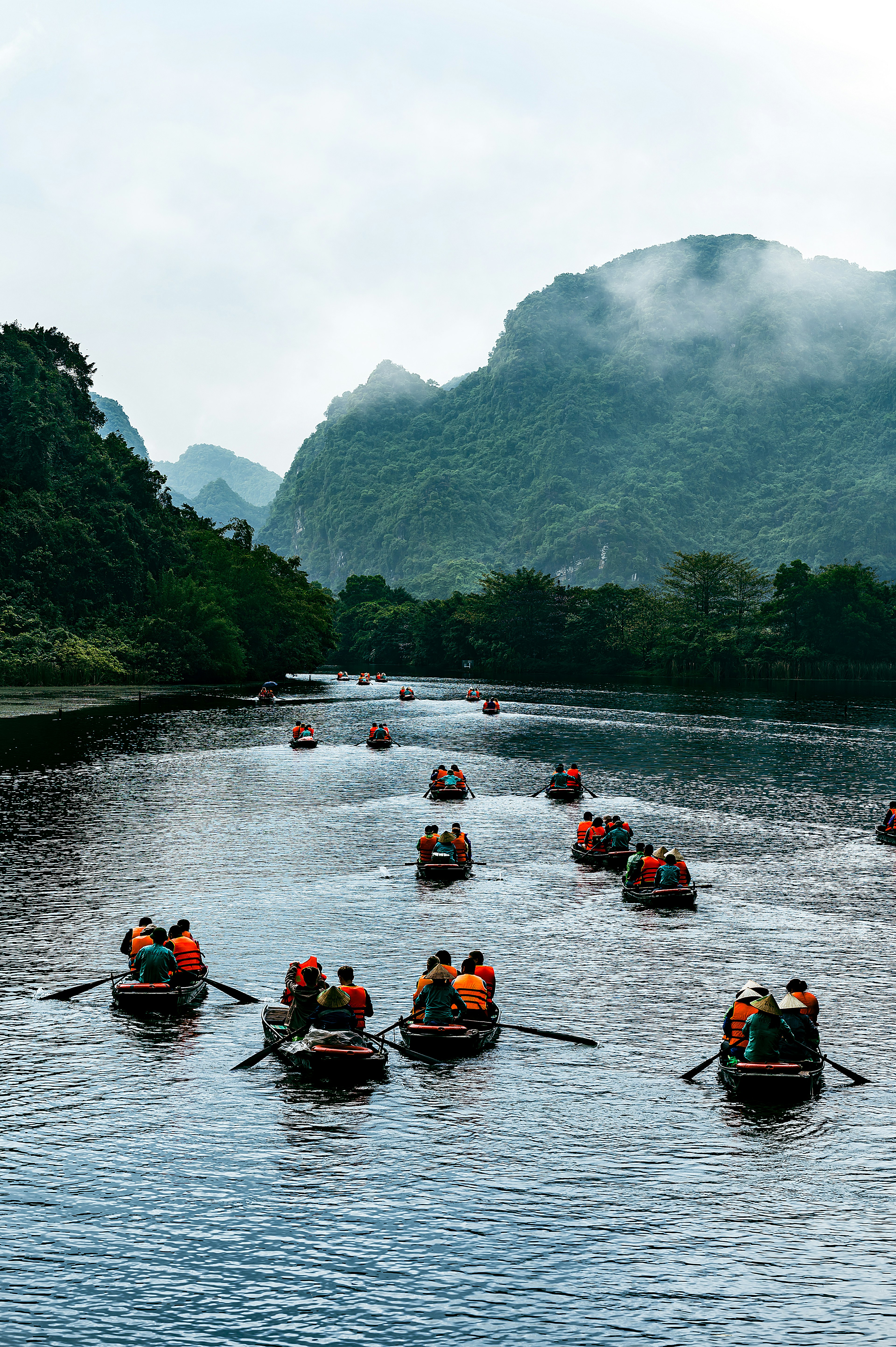 Rowboats on a river surrounded by mountains