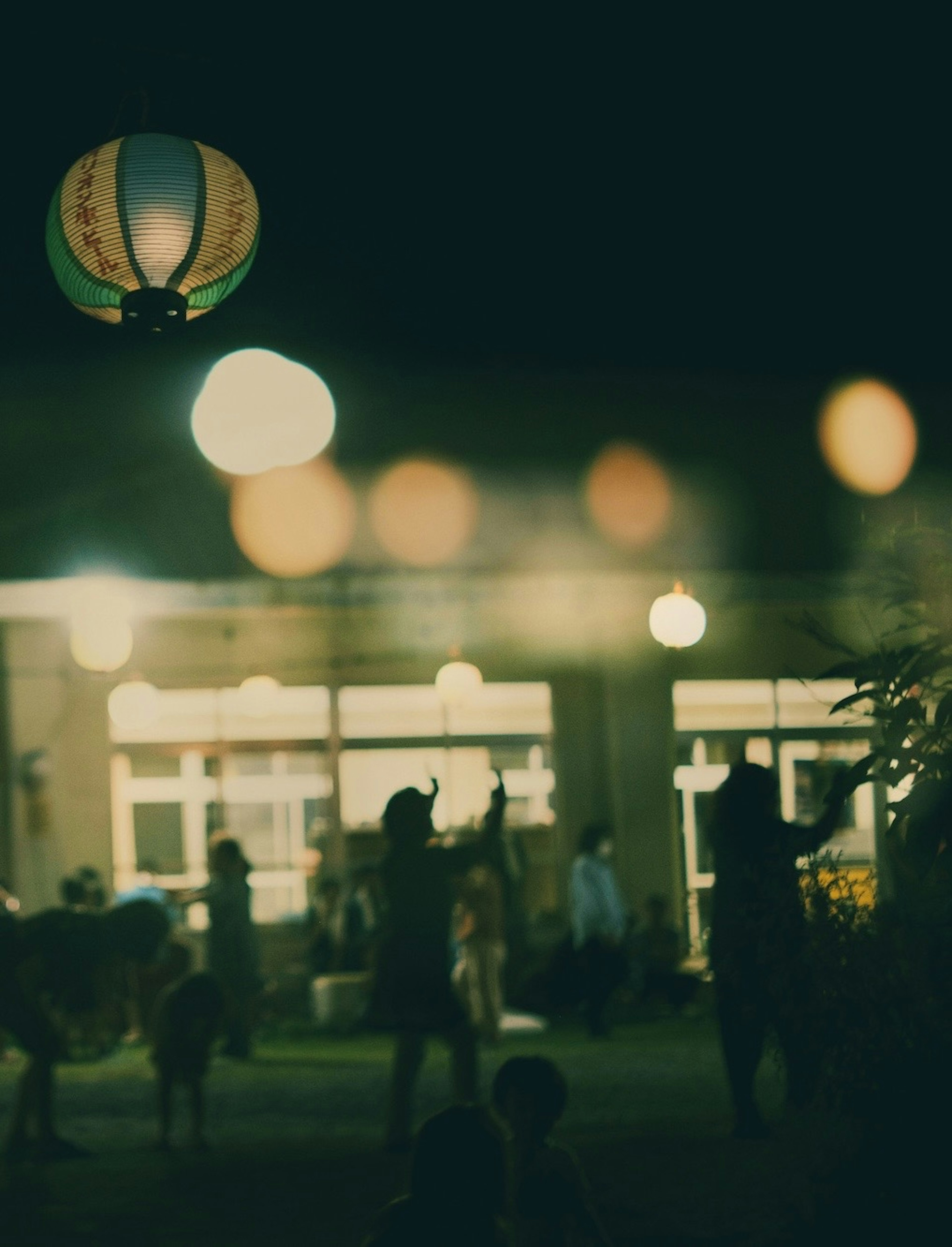 Night festival scene with blurred lights and silhouettes of people