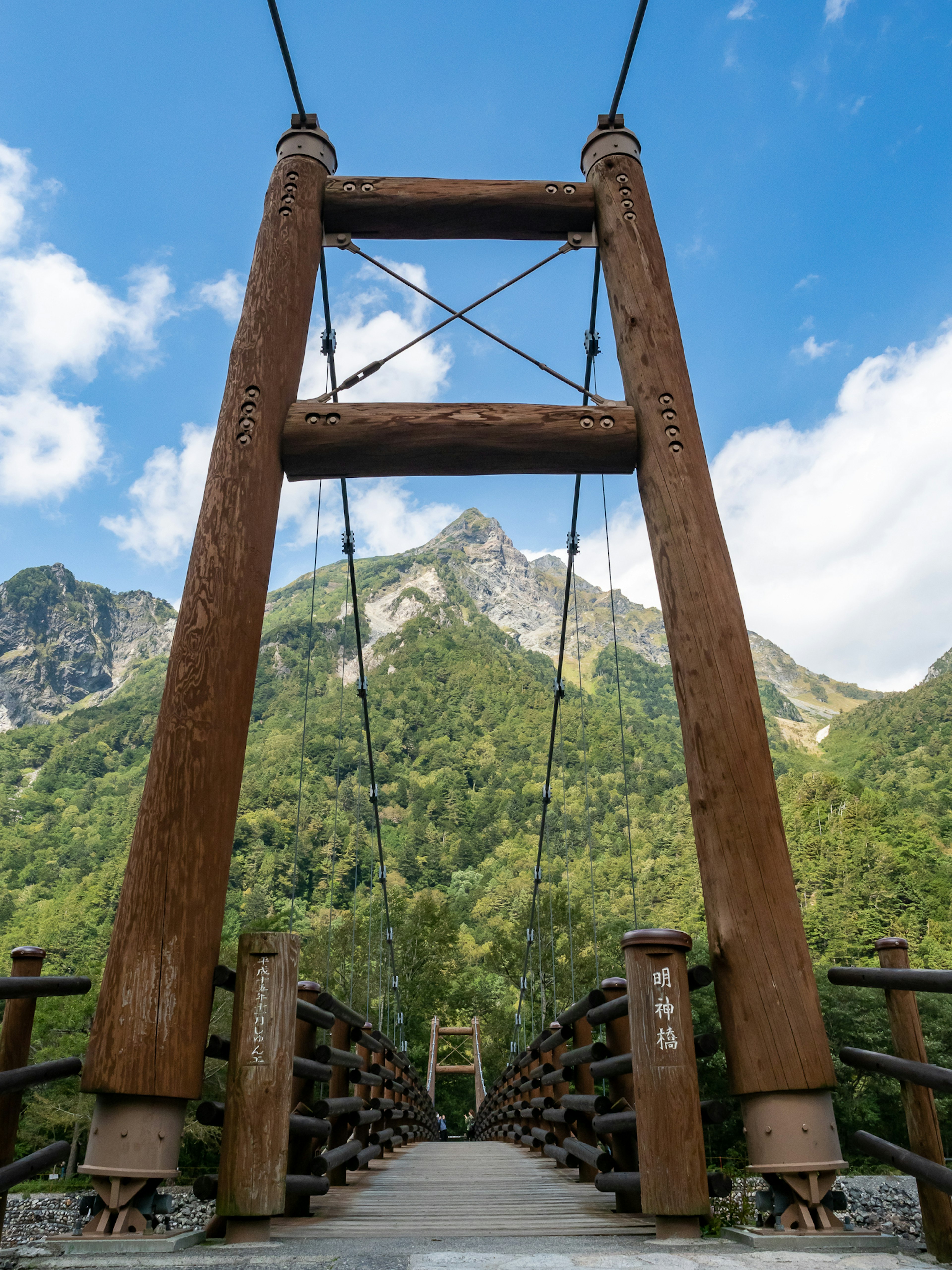 A large wooden suspension bridge set against a mountain landscape