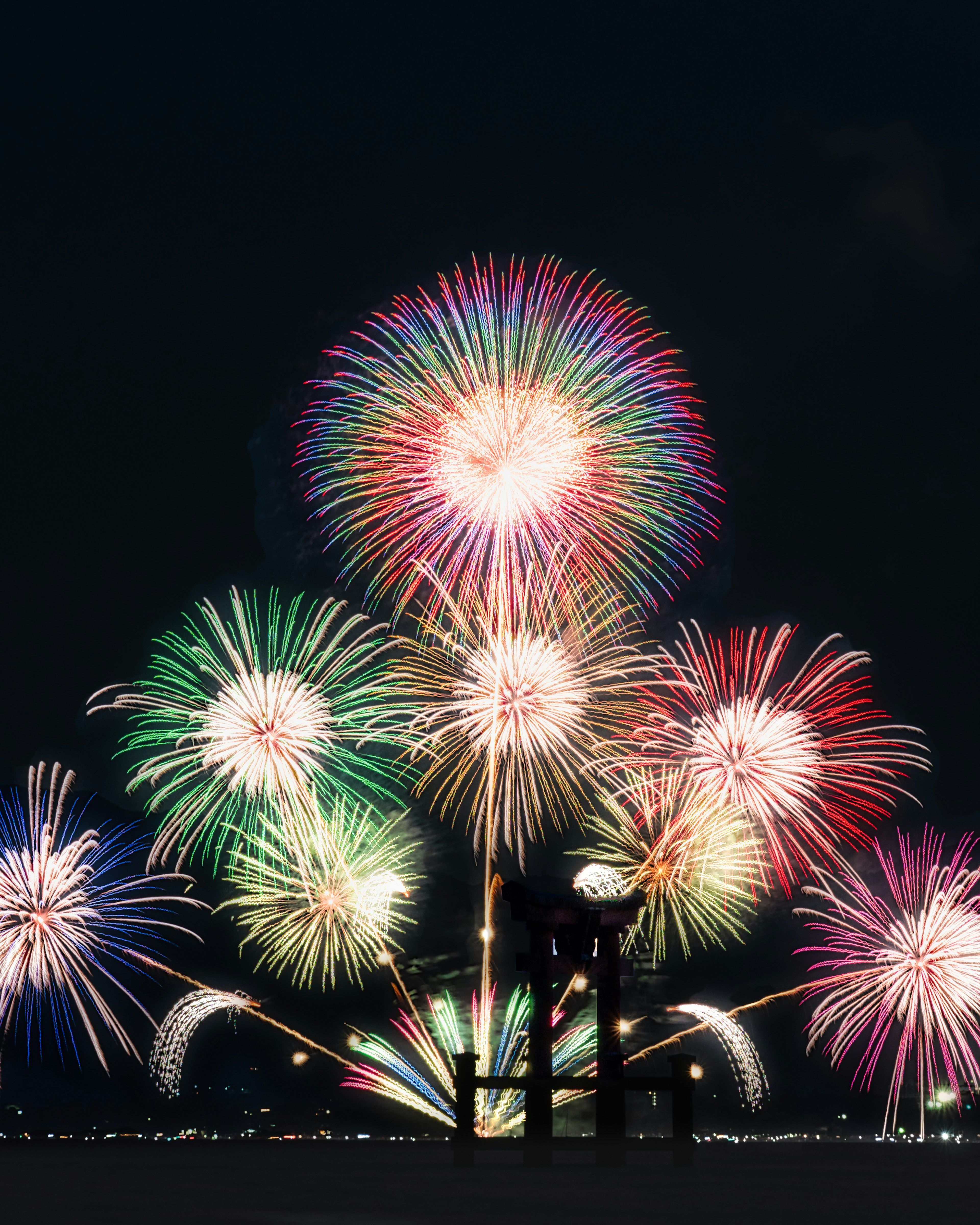 Spectacle de feux d'artifice colorés illuminant le ciel nocturne avec des silhouettes